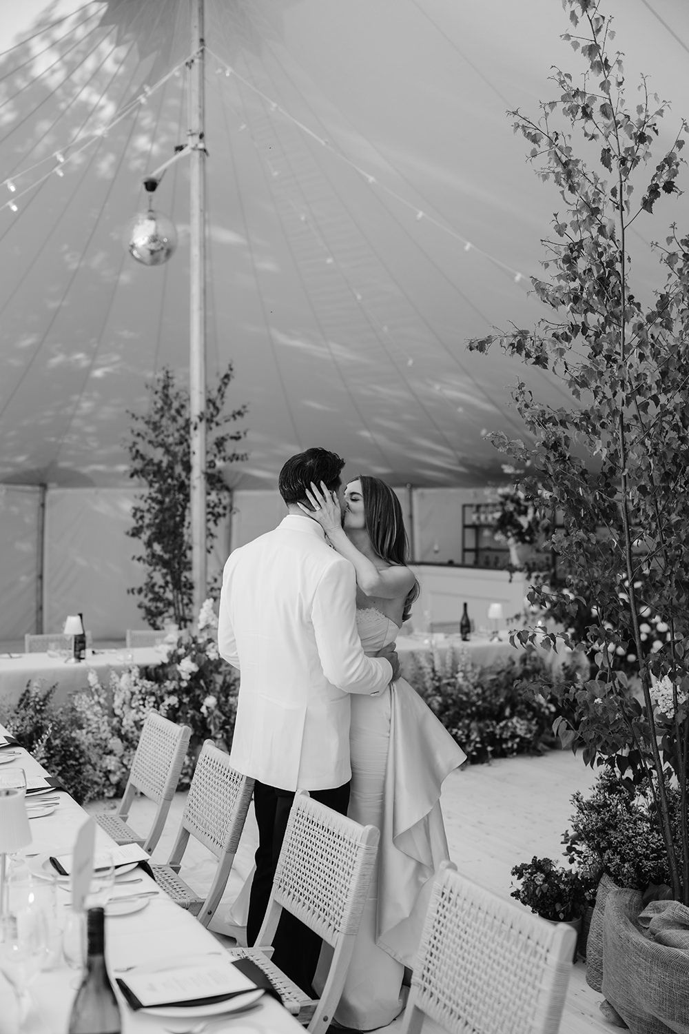 A black and white photo series shows event guests signing a guestbook at a wedding reception under a tent canopy.