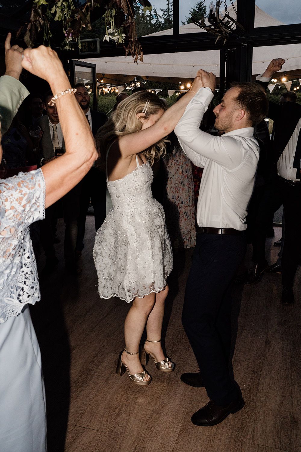 Bride and groom dancing their first dance with friends and family surrounding them.