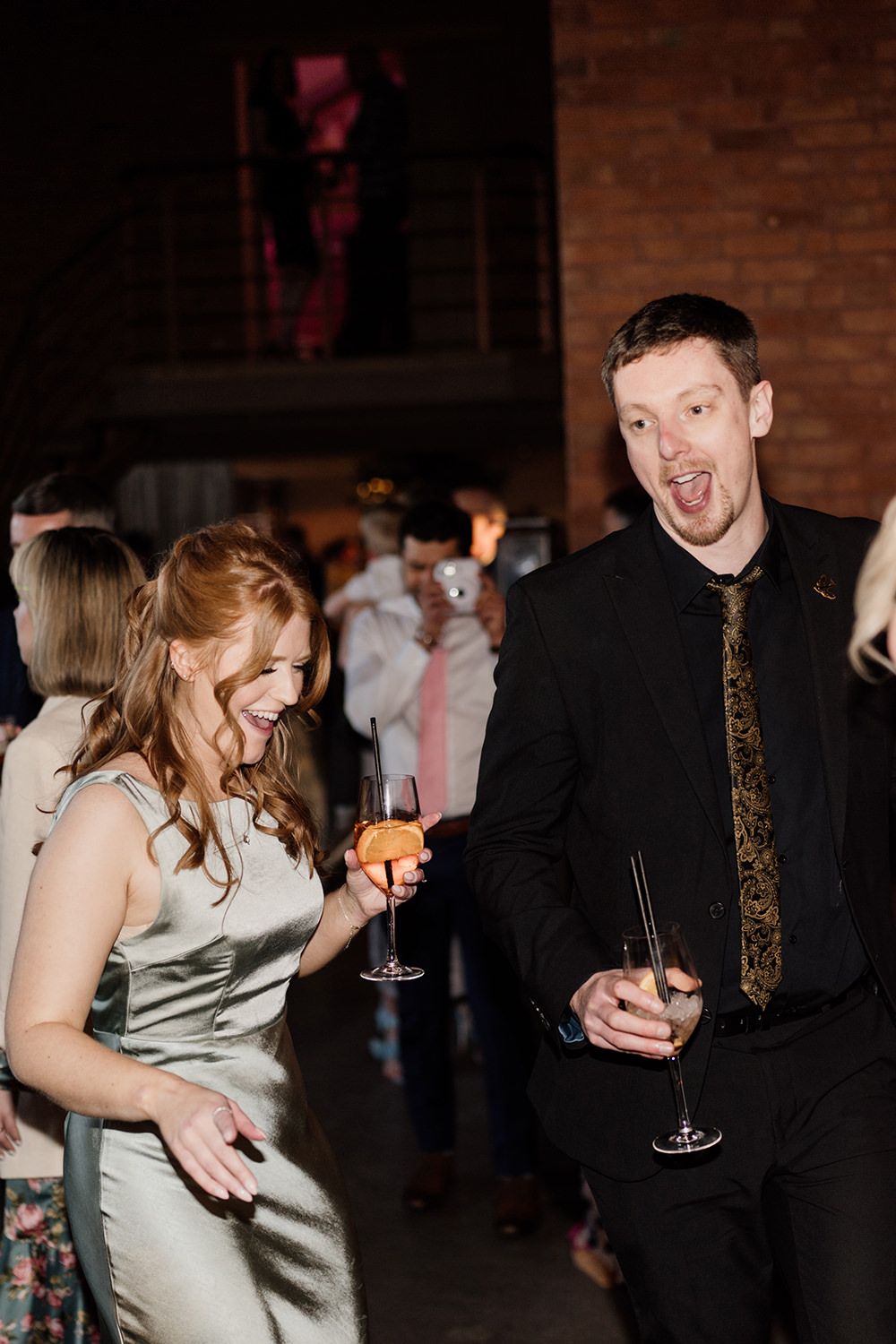 Bridesmaid and wedding guest singing and dancing.