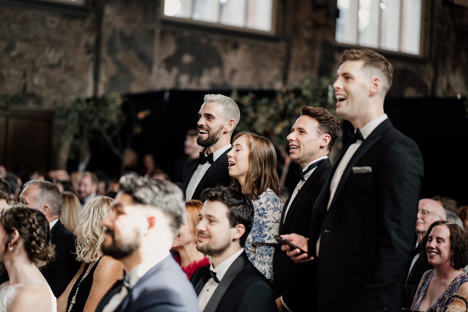 Wedding guests standing singing during the ceremony at Battersea Arts Centre.