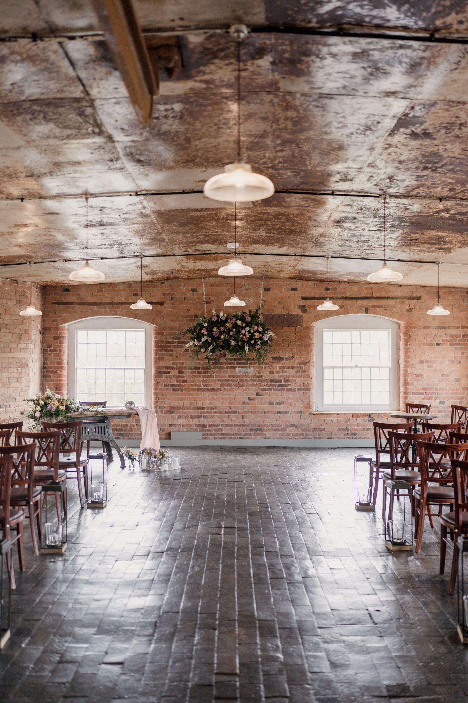 Rustic brick venue with wooden chairs arranged for a wedding ceremony.