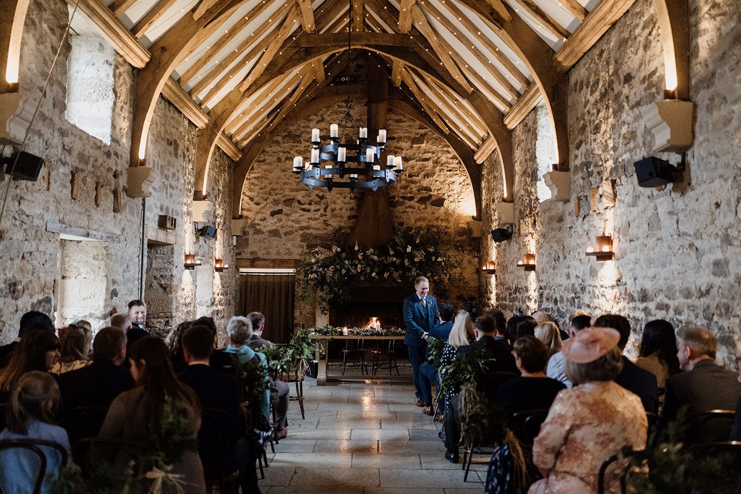 Wedding guests seated in Healey Barn as the groom welcomes them.