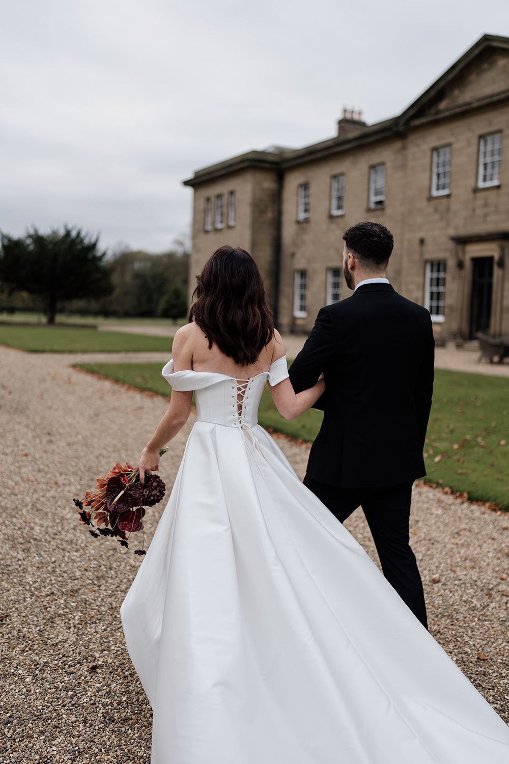 Bride and groom holding hands, smiling, laughing while working through the grounds of Rise Hall.