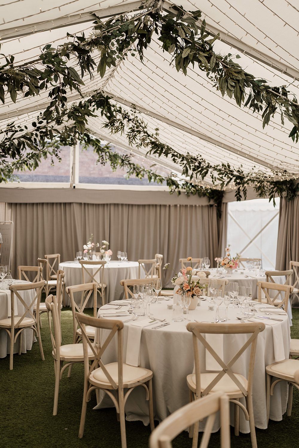 The wedding reception room at The Holford Estate ready for speeches, tables have white cloths with minimal flowers.