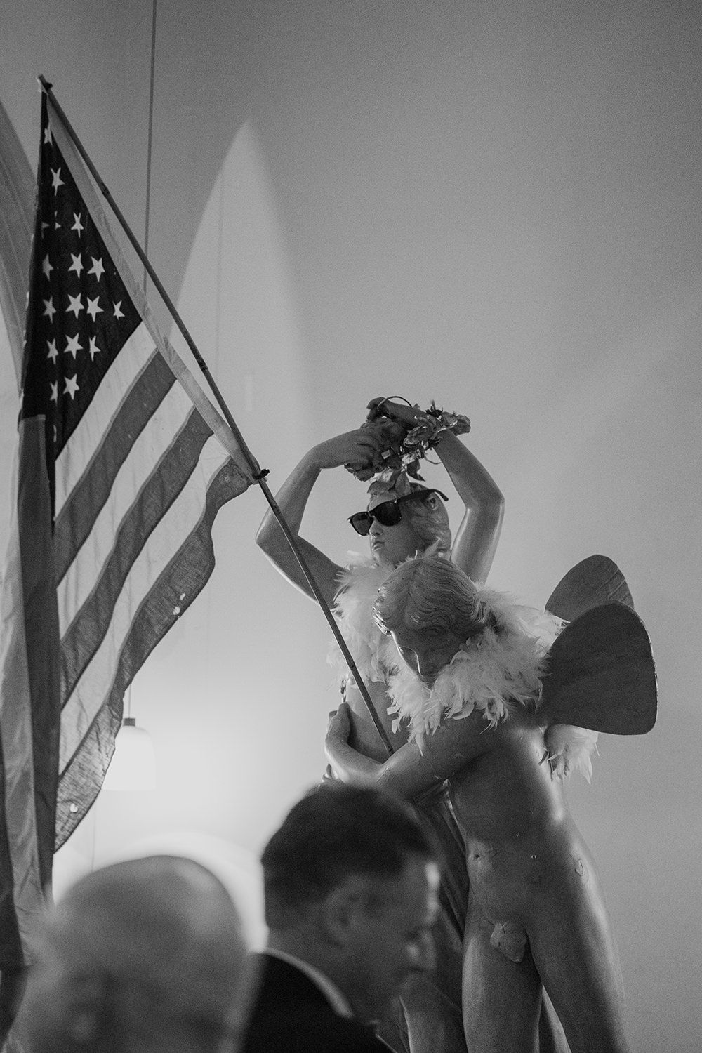 Statue at Battersea Arts Centre wearing sunglasses, a feather bowa holding a USA flag.