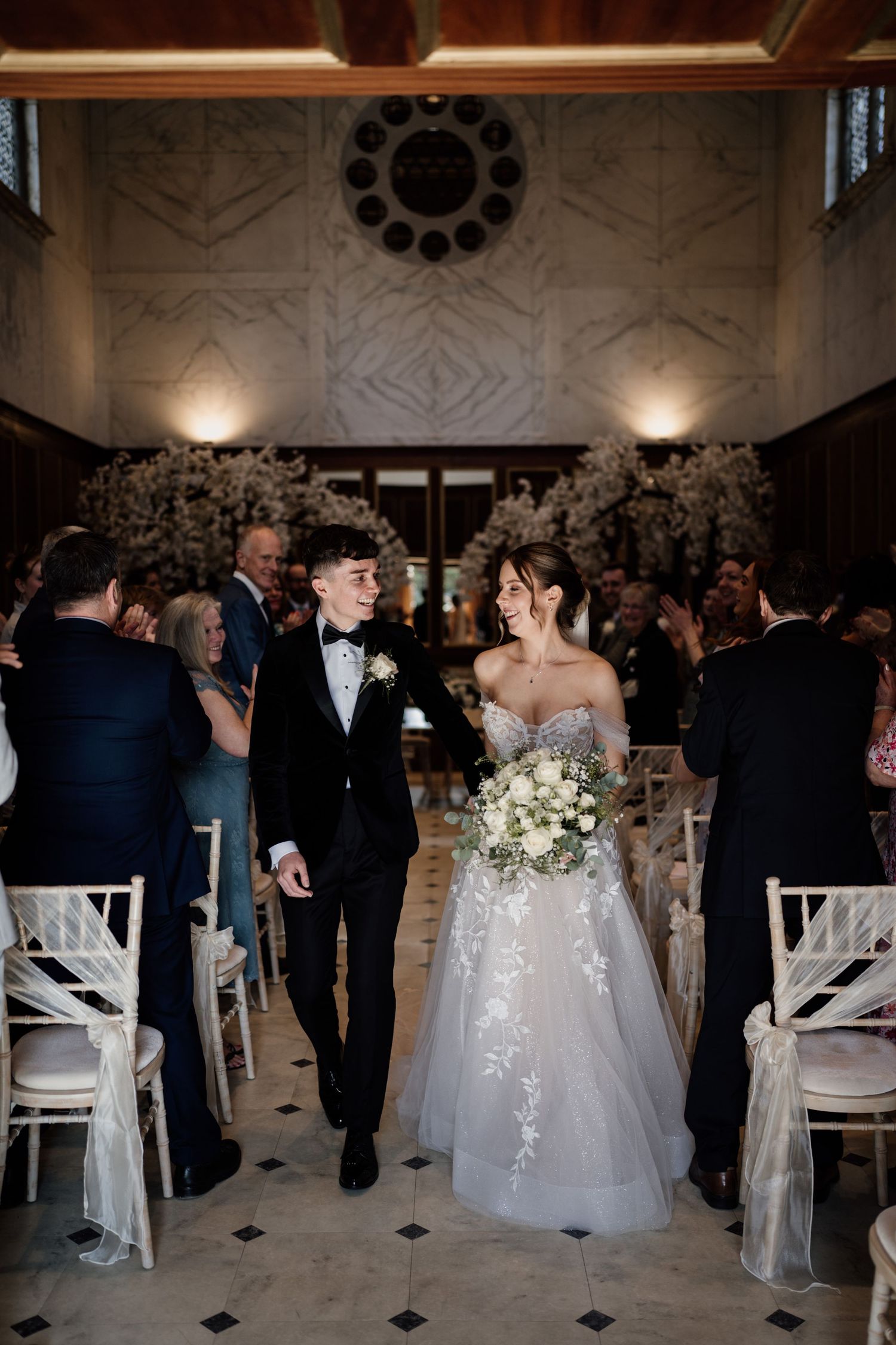 Bride and groom leaving their wedding ceremony with guests in the background.