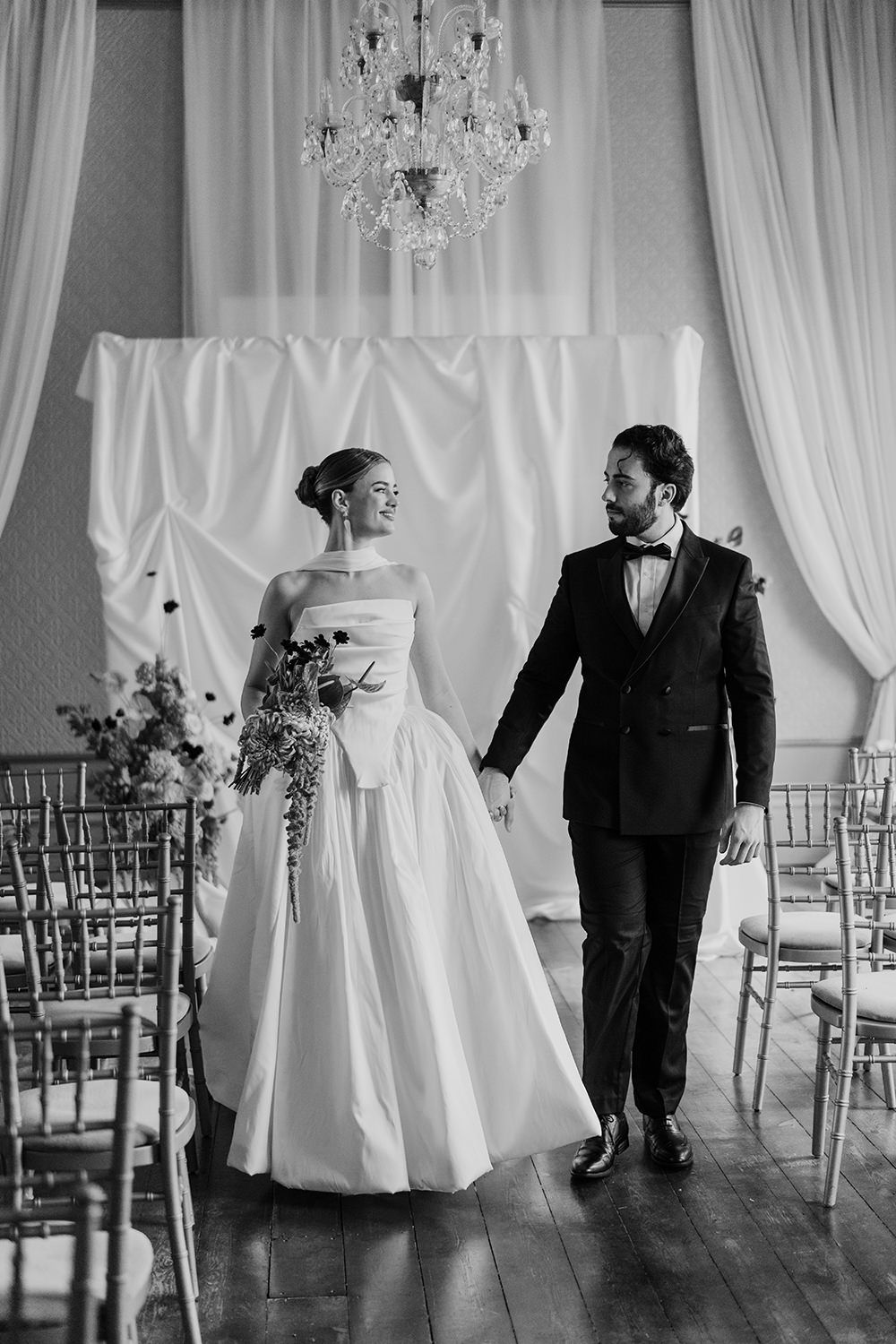 Bride and groom holding hands walking into their wedding ceremony at Rise Hall.