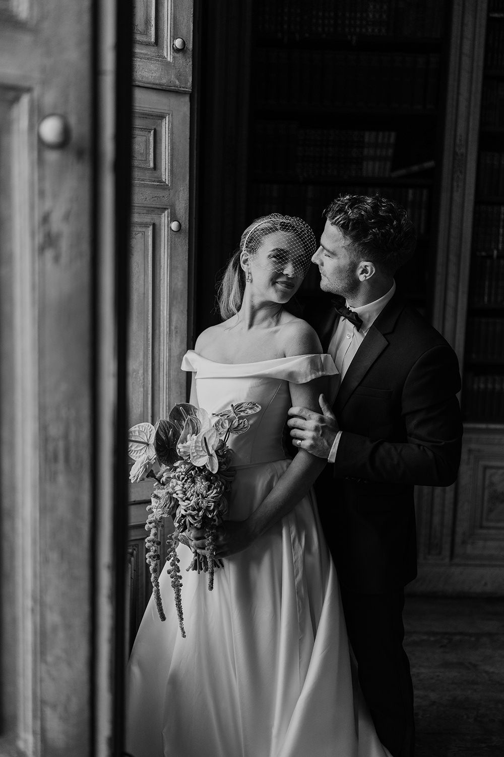 Bride and groom face towards each other while being lit by a grand window at Rise Hall.