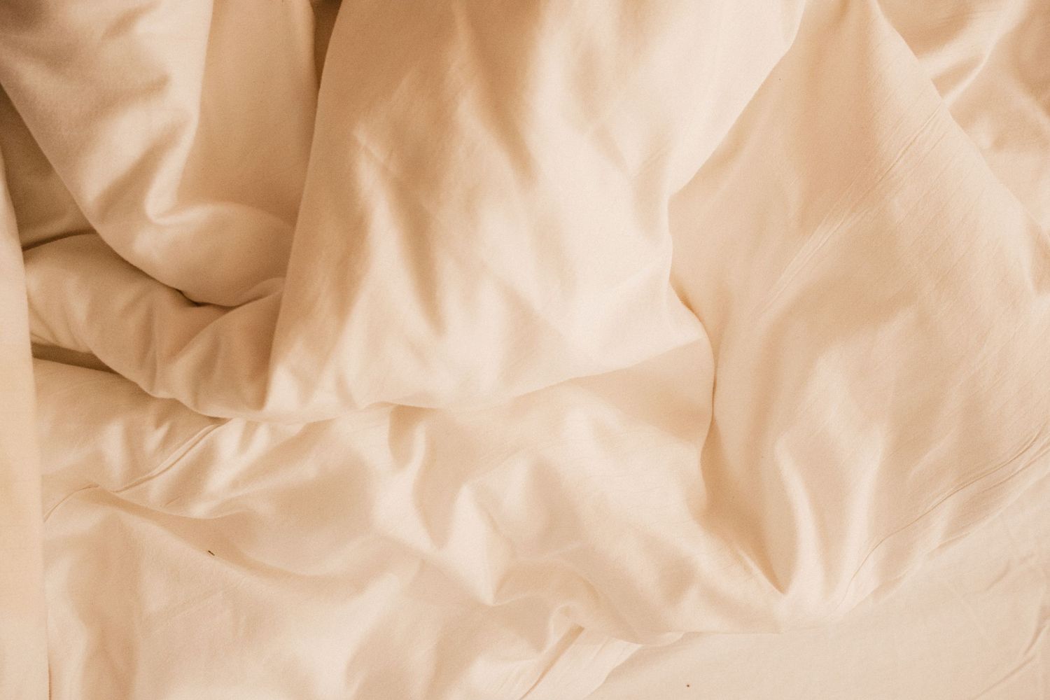 Crumpled beige paper texture background with soft shadows and wrinkled surface details.