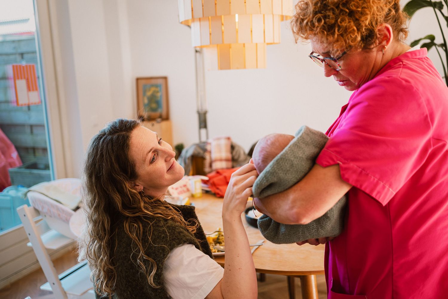 Kraamzorg laat baby aan moeder zien tijdens kraambezoek, kraamtijdfotograaf Leiden