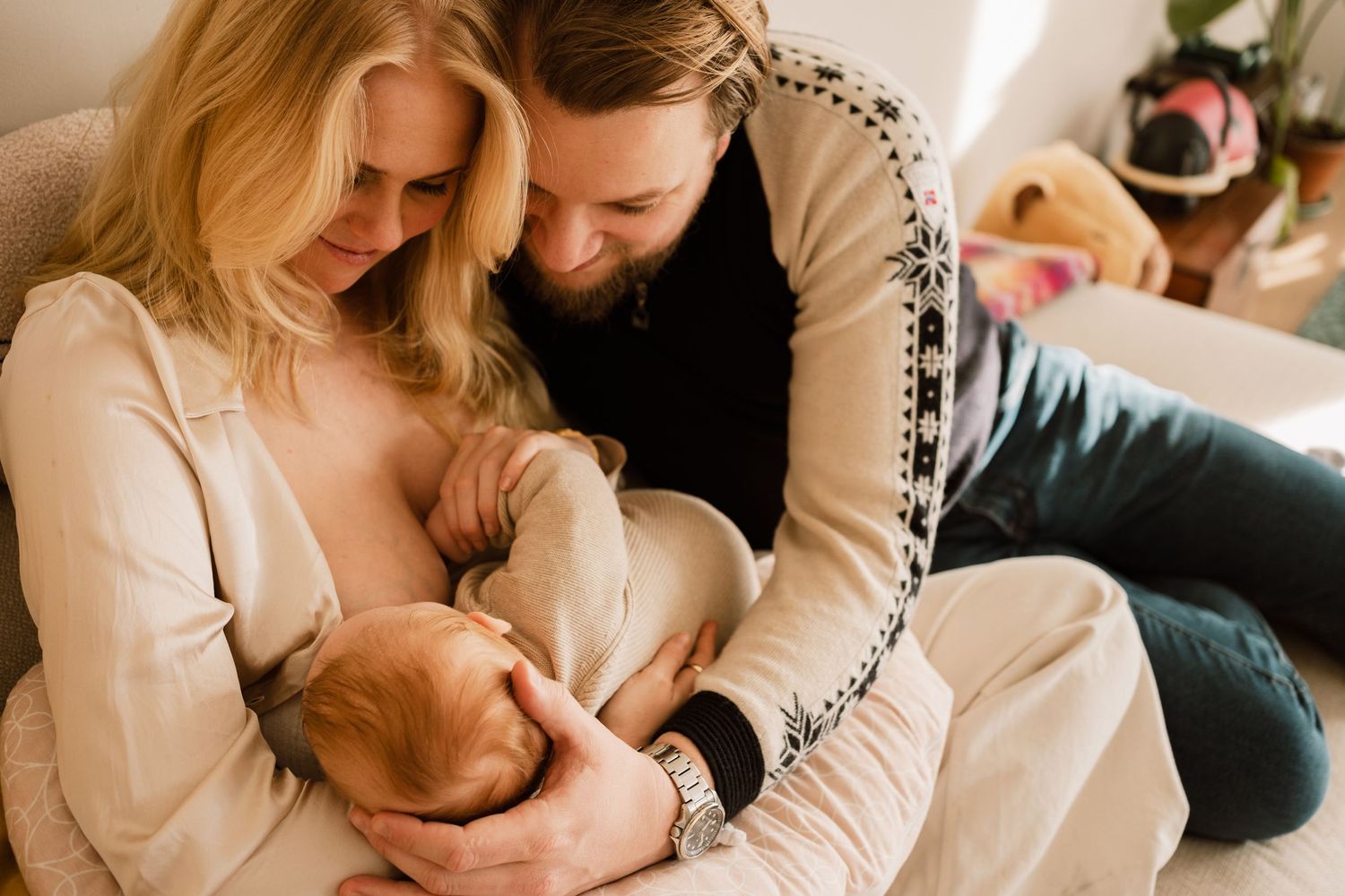 Documentaire newbornfotografie Den Haag door Mama Nora: papa en mama kijken liefdevol naar baby die de borst krijgt.