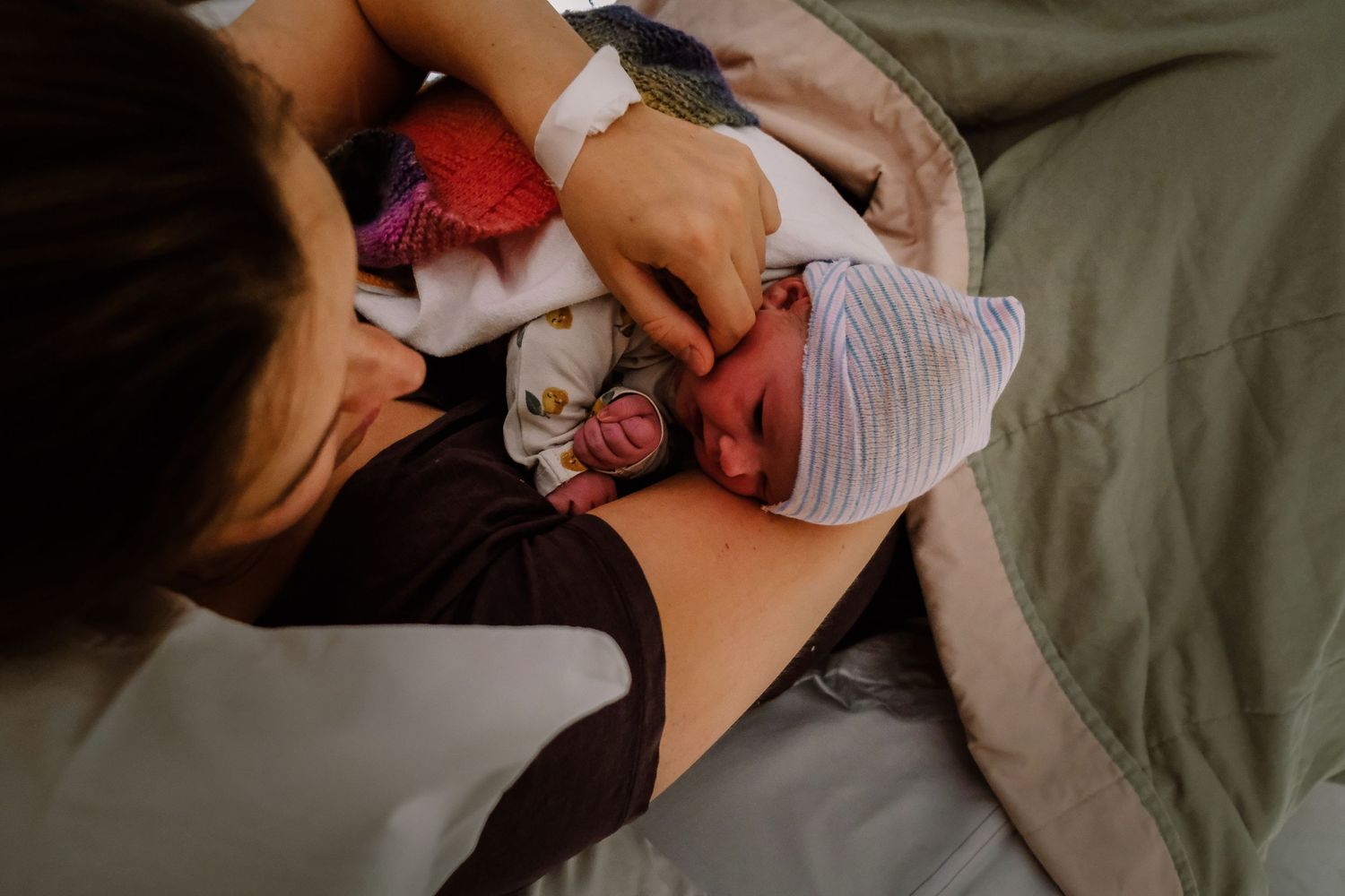 A mother tenderly holds her newborn baby in a hospital bed, sharing a precious first bonding moment after birth.