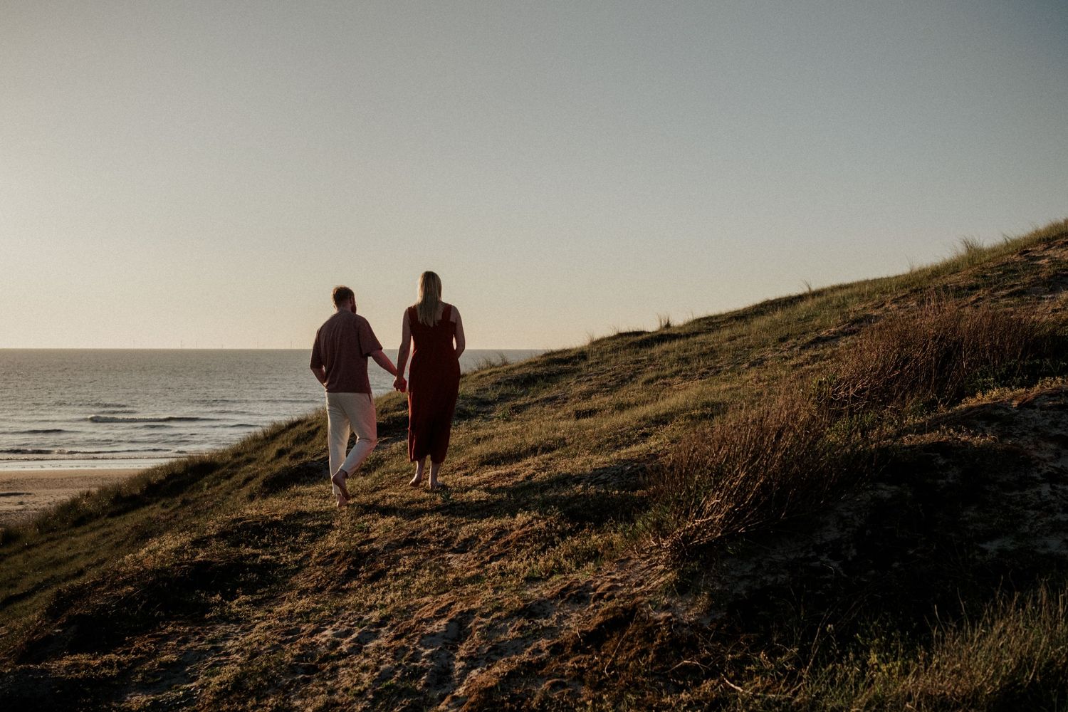 Sunset zwangerschapsshoot aan het strand in Zuid-Holland, Noordwijk. Liefdevol, hand in hand bij zonsondergang.