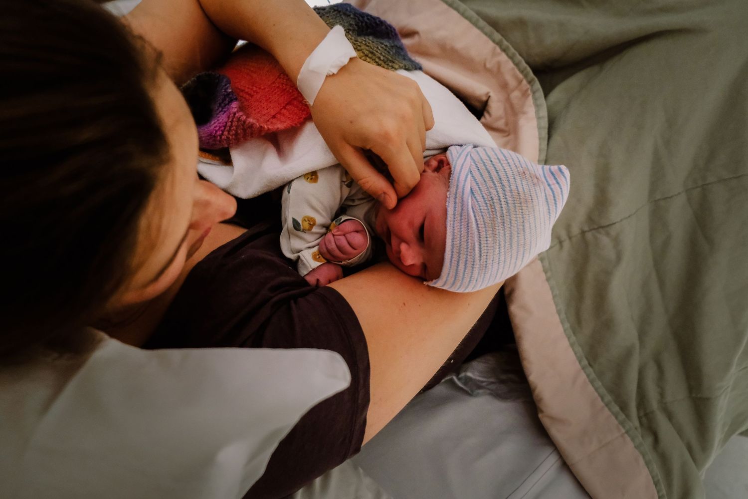 A mother tenderly holds her newborn baby in a hospital bed, sharing a precious first bonding moment after birth.