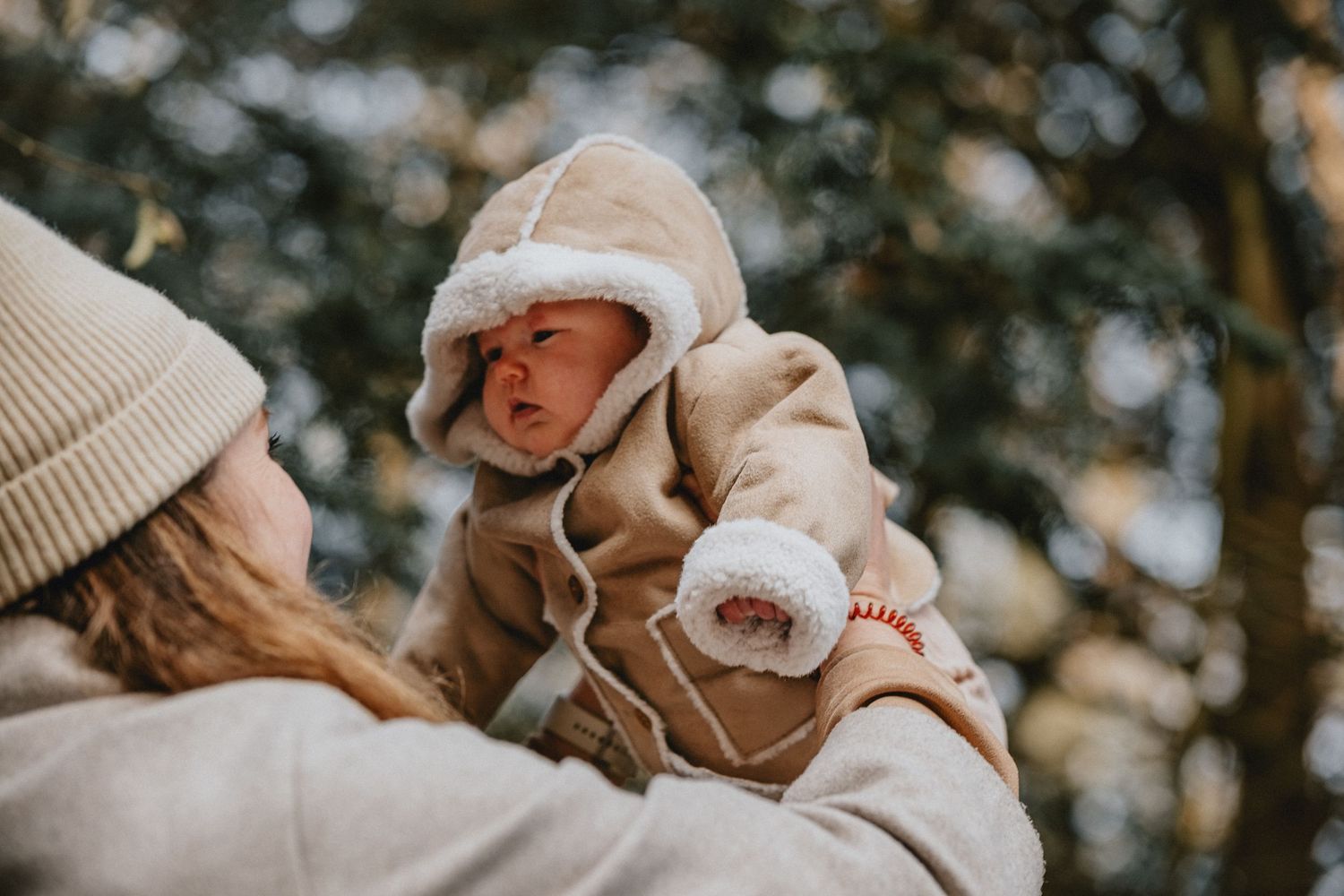 Liefdevol moment tijdens een buitenfotoshoot: mama houdt baby vast in de winterse natuur bij Leiden.