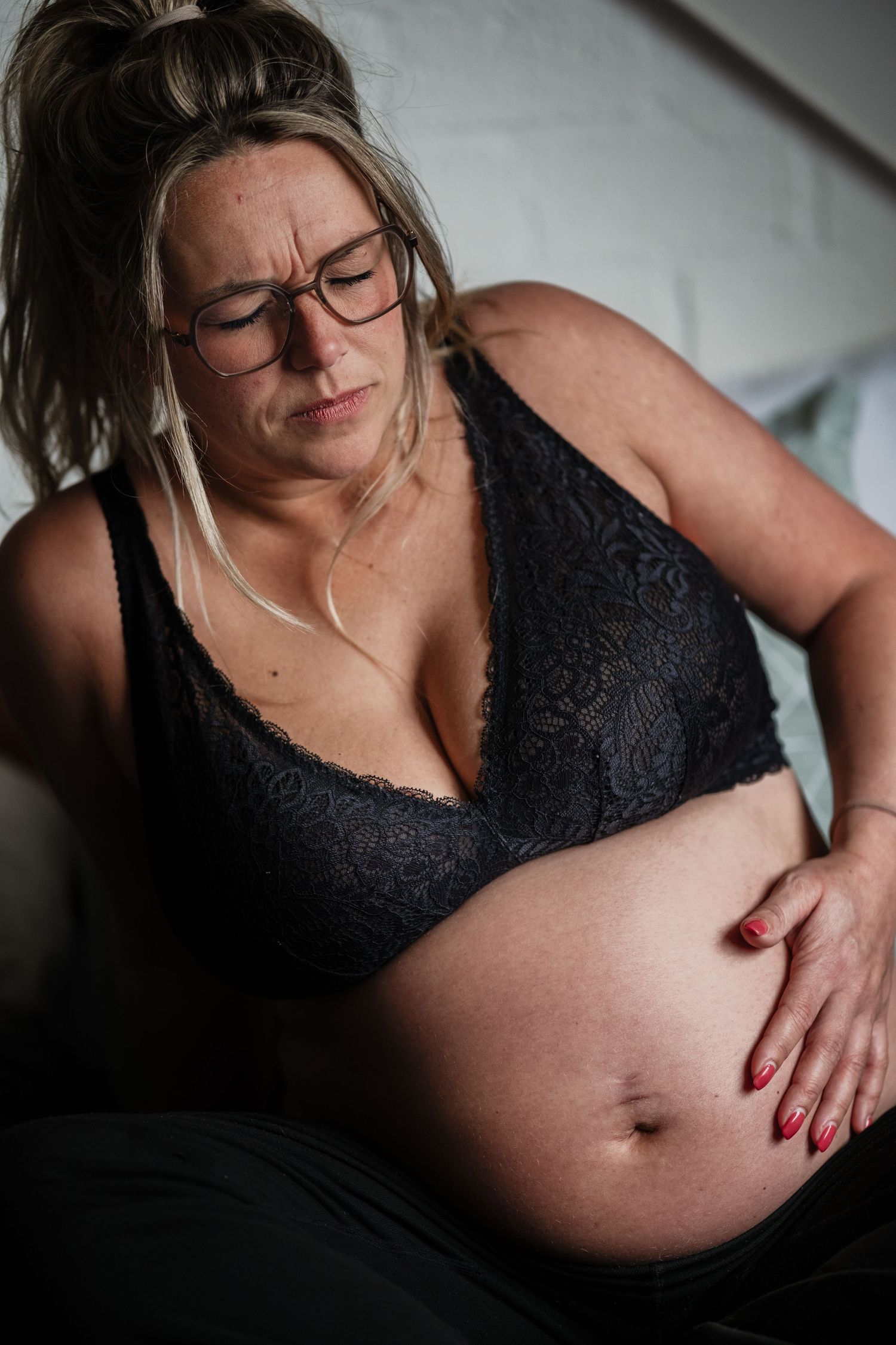 Vrouw vangt weeën op in bed tijdens bevalling, geboortefotografie Den Haag door Mama Nora Fotografie