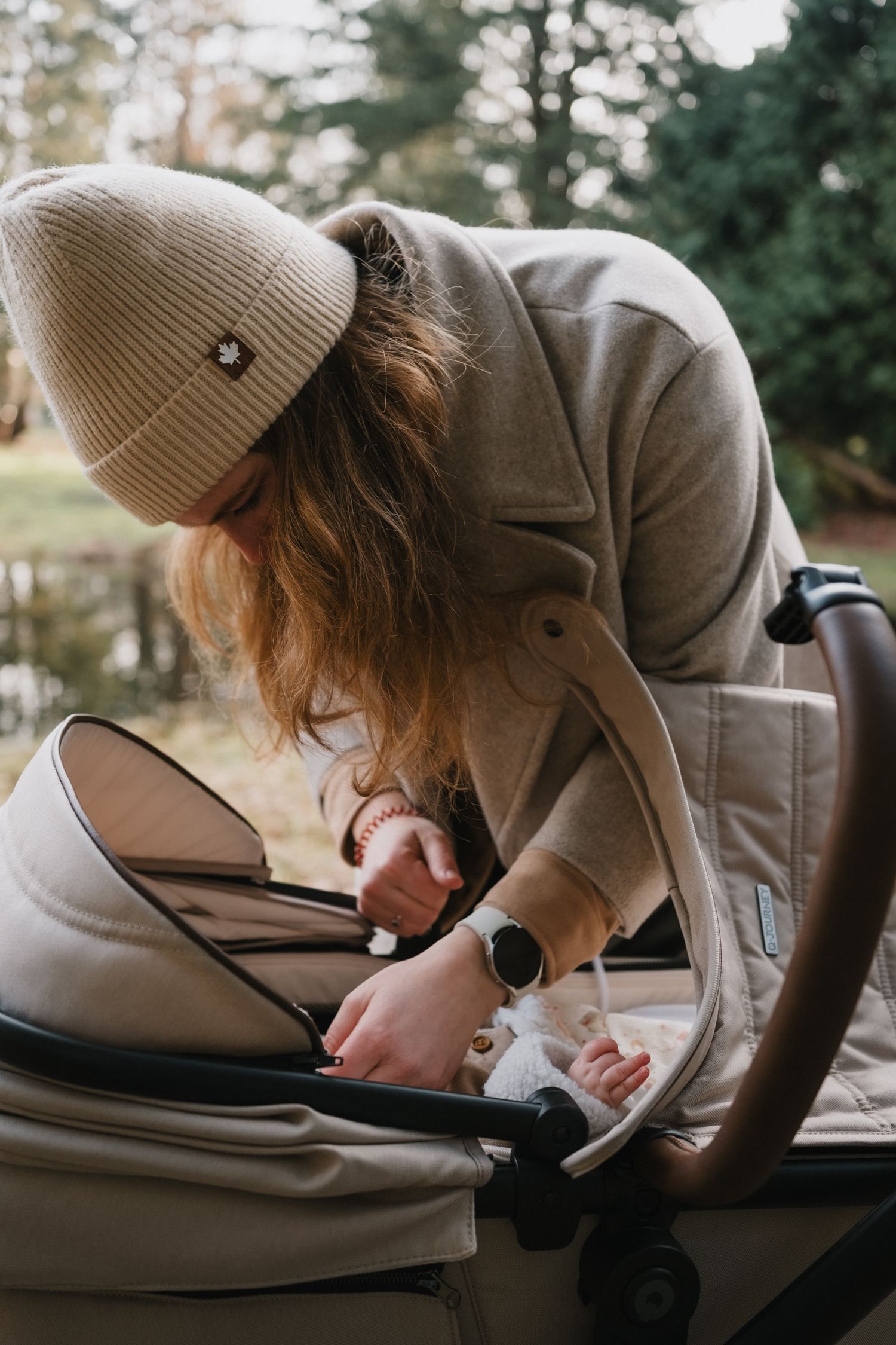 Moeder kijkt liefdevol naar haar baby in de kinderwagen tijdens een wandeling op Landgoed Huys te Warmond.