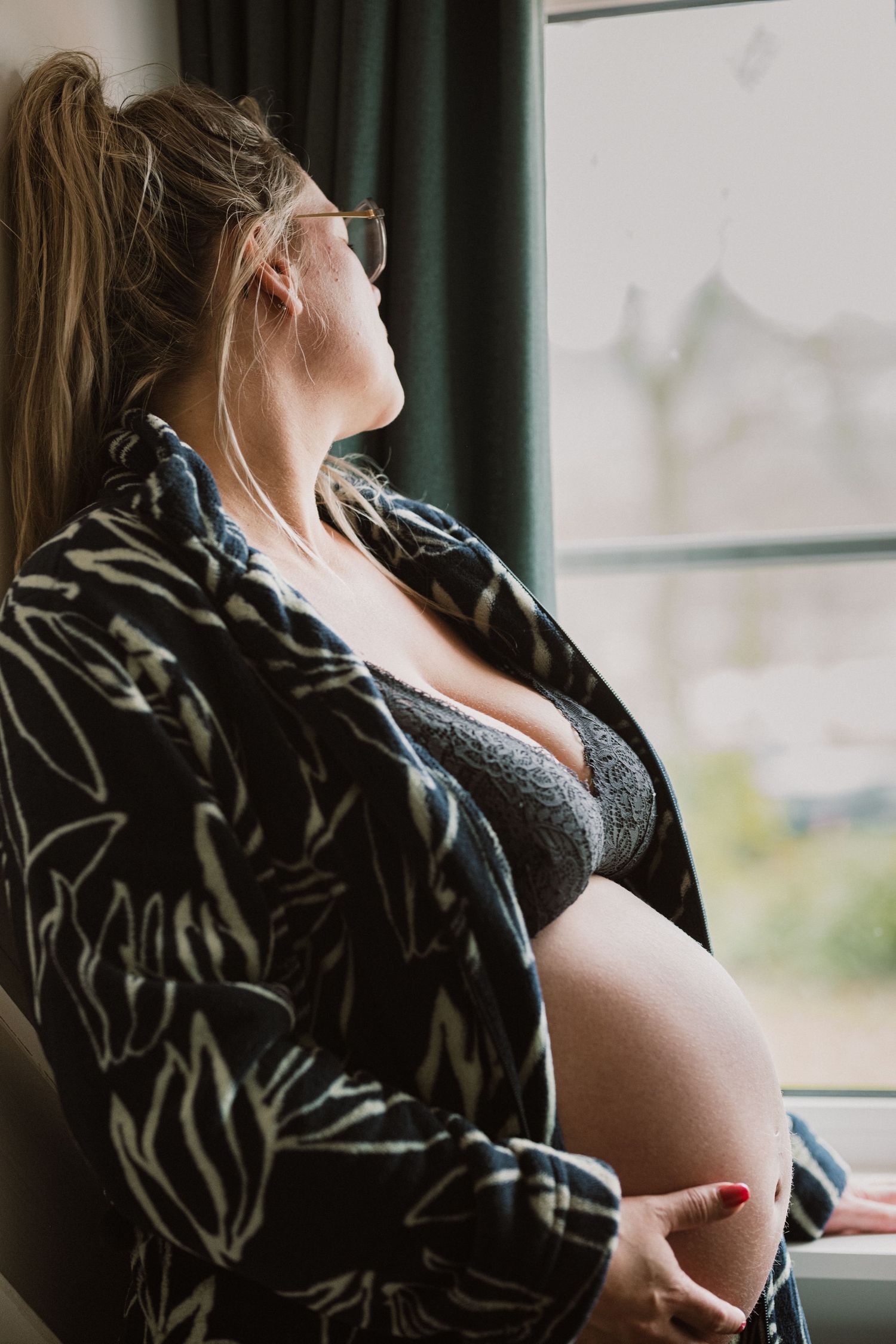 Zorgzame zwangerschapsshoot die een verhaal vertelt in Bollenstreek door fotograaf Mama Nora: zwangere vrouw bij het raam.