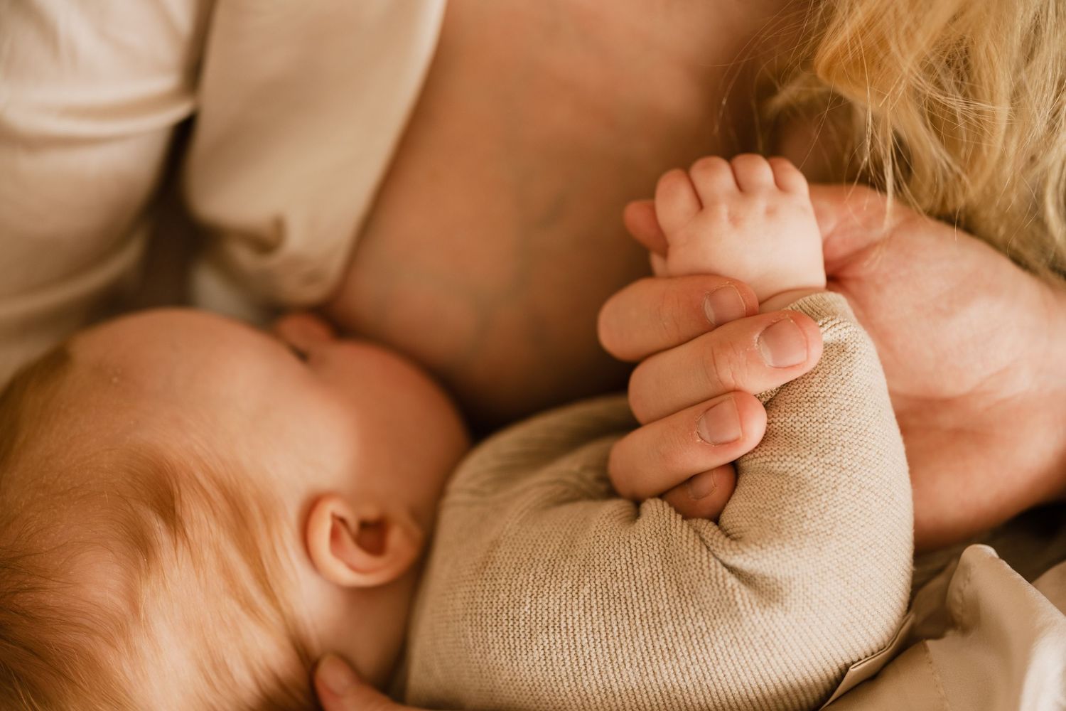 Baby drinkt aan de borst terwijl moeder handje vasthoudt, kraamreportage Den Haag