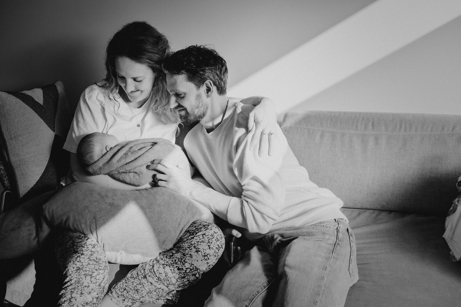 Vader en moeder met baby in warm licht, kraamtijdfotograaf Leiden