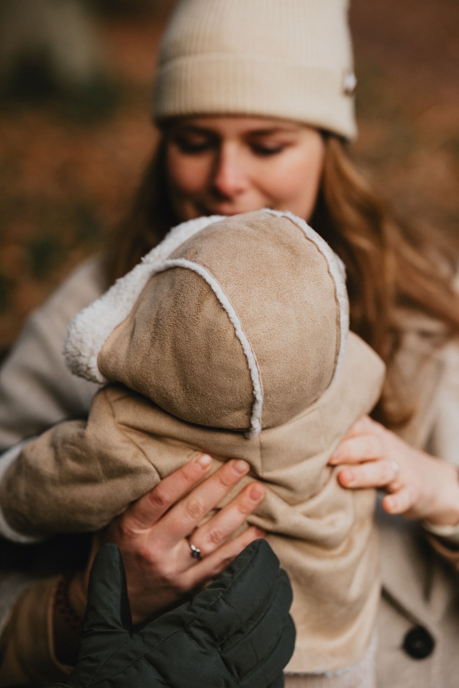 Moeder tilt haar baby op tussen de winterse bomen op Landgoed Huys te Warmond voor een spontane gezinsfoto.
