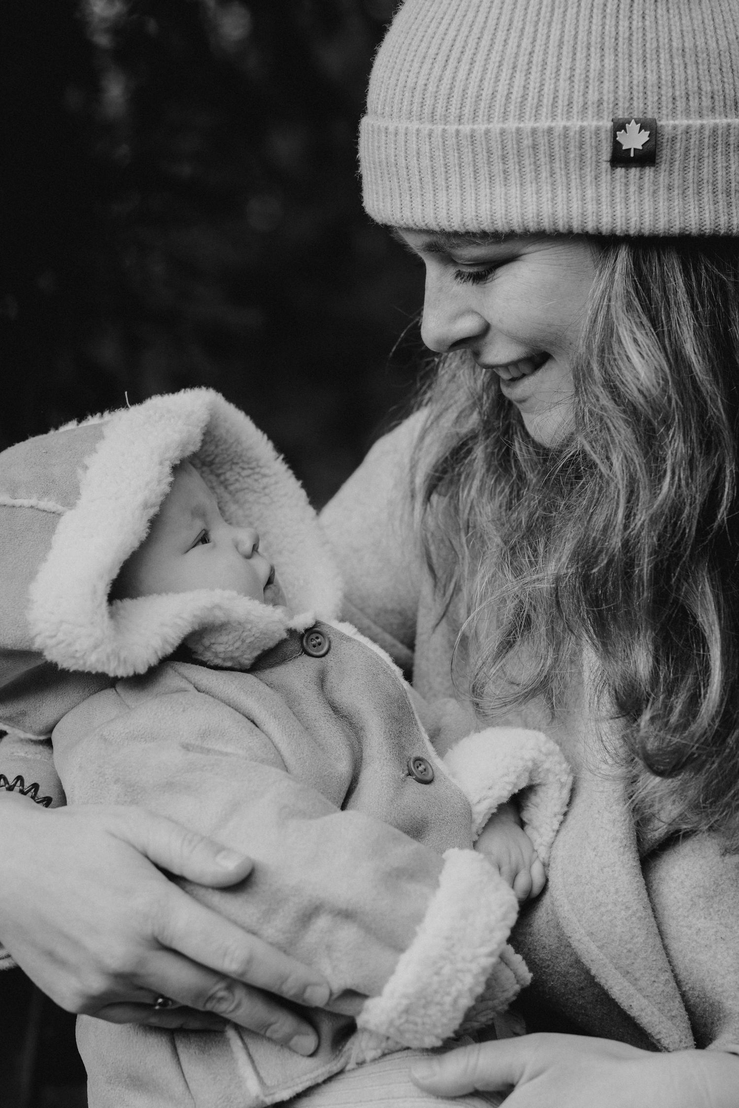 Intiem moment tussen moeder en baby in het bos van Warmond tijdens een winterse fotoshoot in zwart wit.