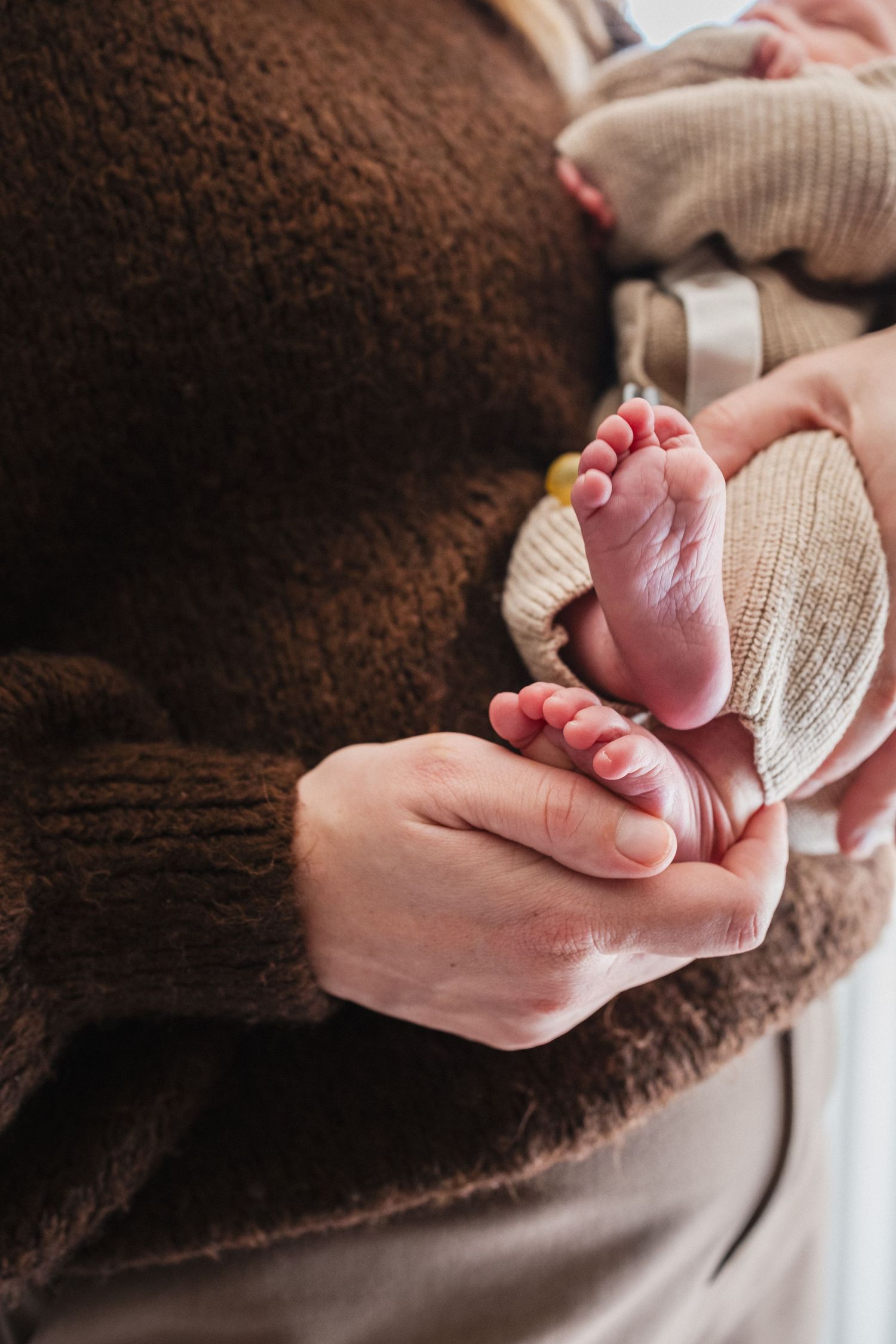 Pasgeboren babyvoetjes in handen van partner, documentaire geboortfotografie Mama Nora Fotografie