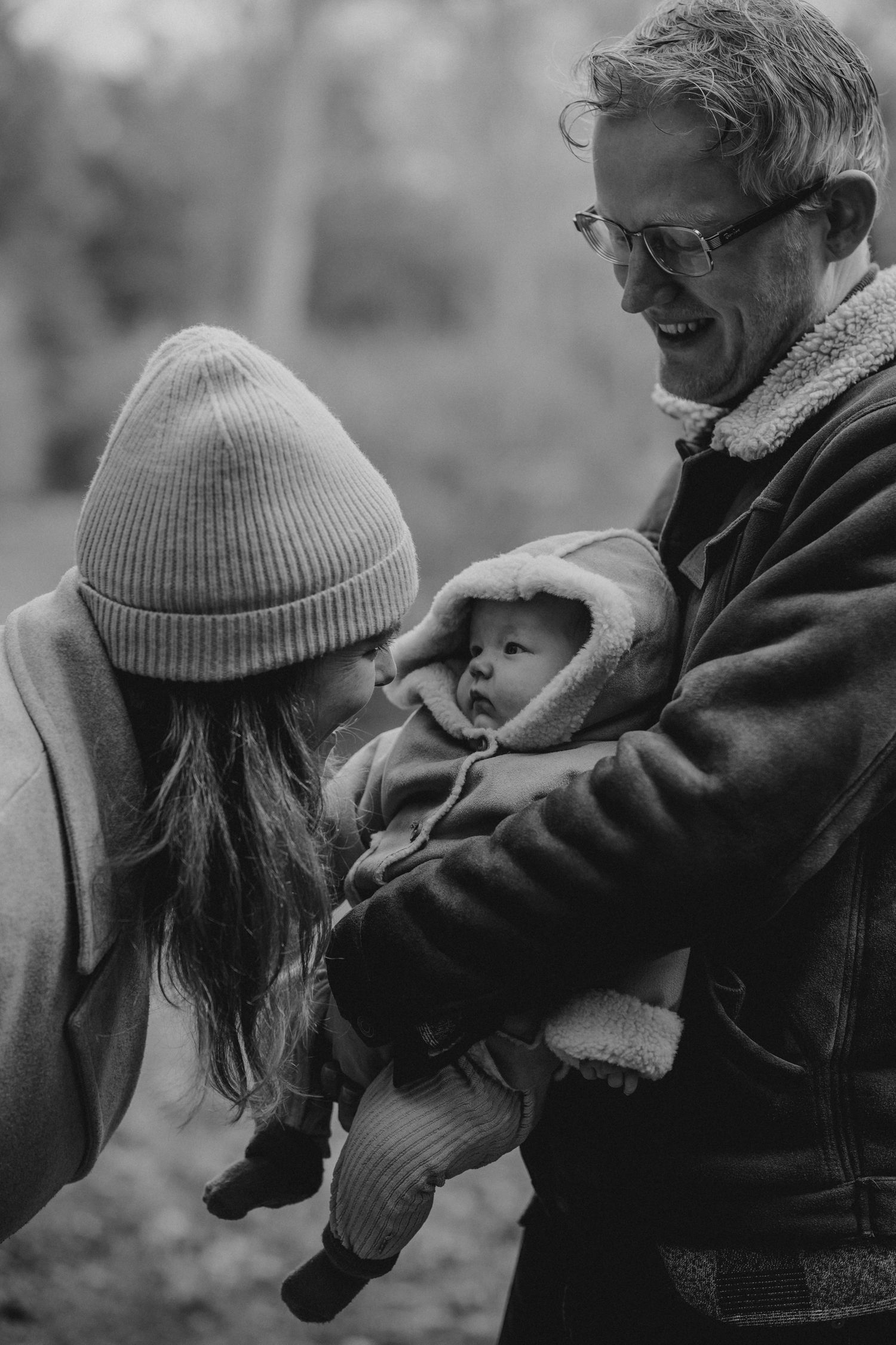 A series of black and white photos showing tender moments between a parent and baby in winter clothing.