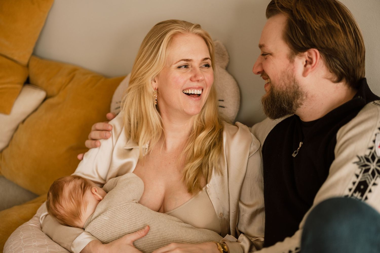 Couple sharing intimate moments and laughter while relaxing together on a couch in a warm-lit room.