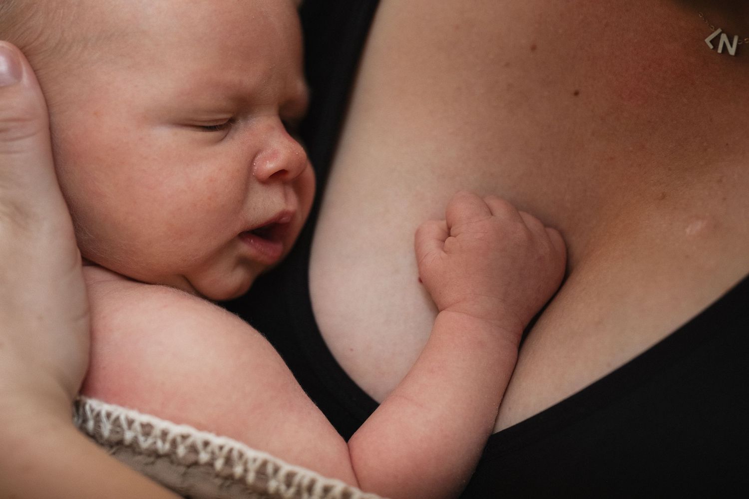 Mother tenderly holding her newborn baby skin-to-skin in a close nurturing embrace.