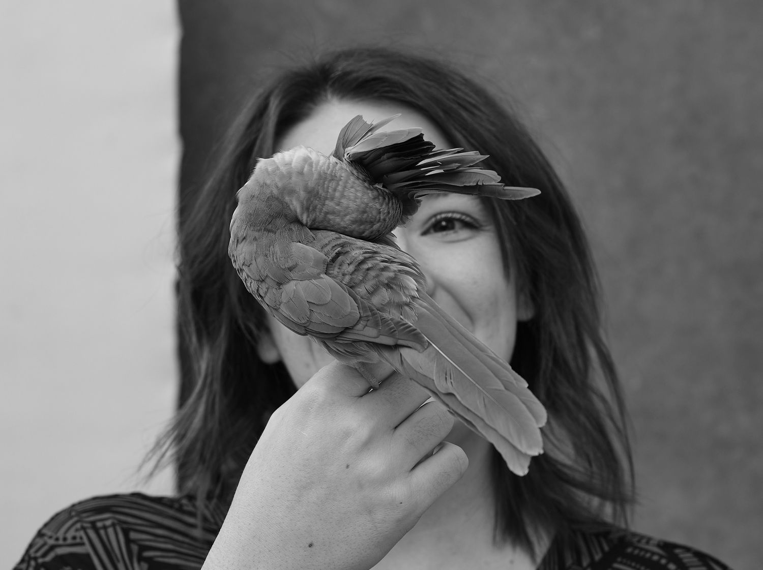 A joyful interaction between a person and their pet bird in black and white photography.