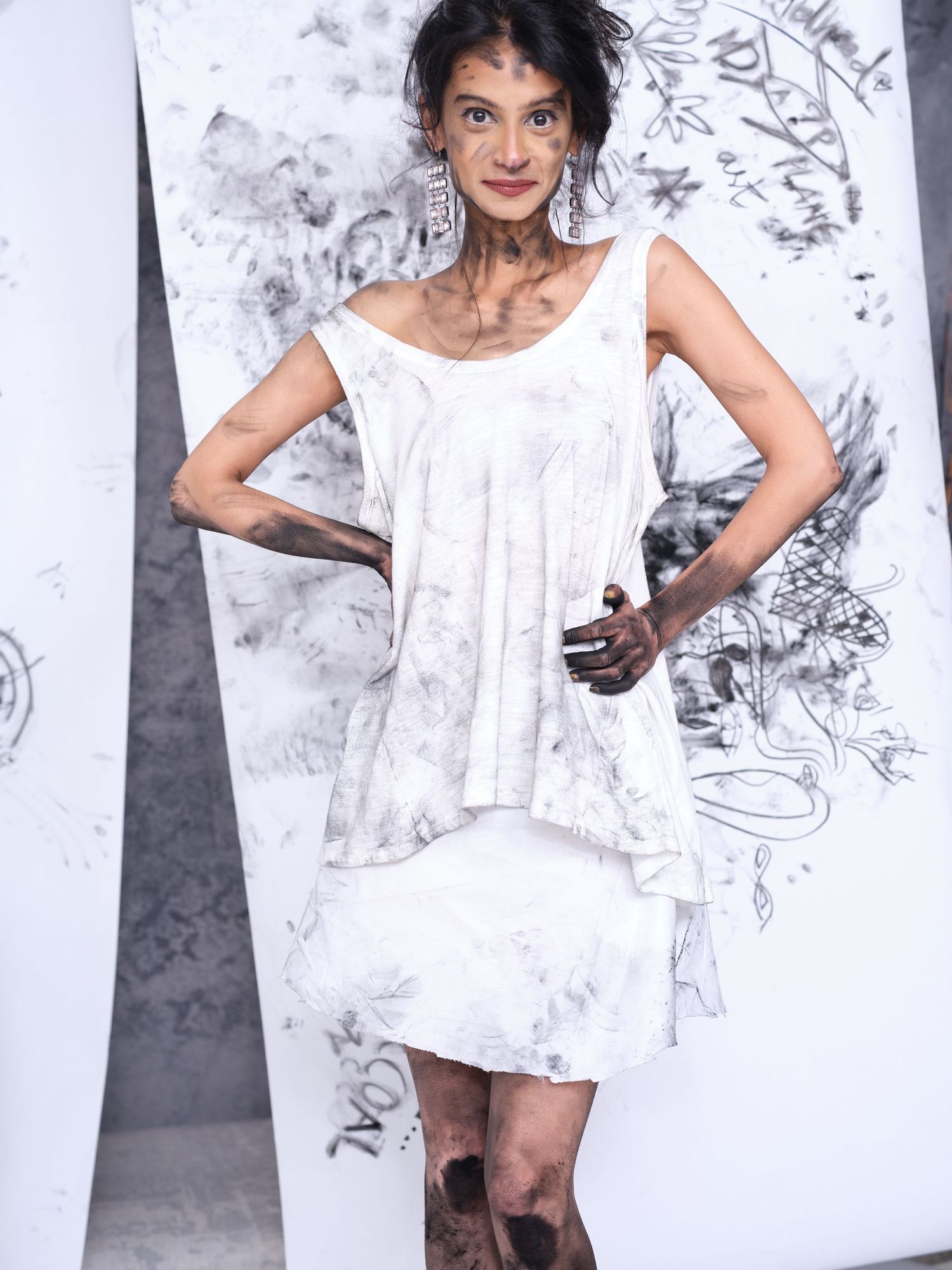 Full length portrait in white dress against artistic charcoal backdrop.