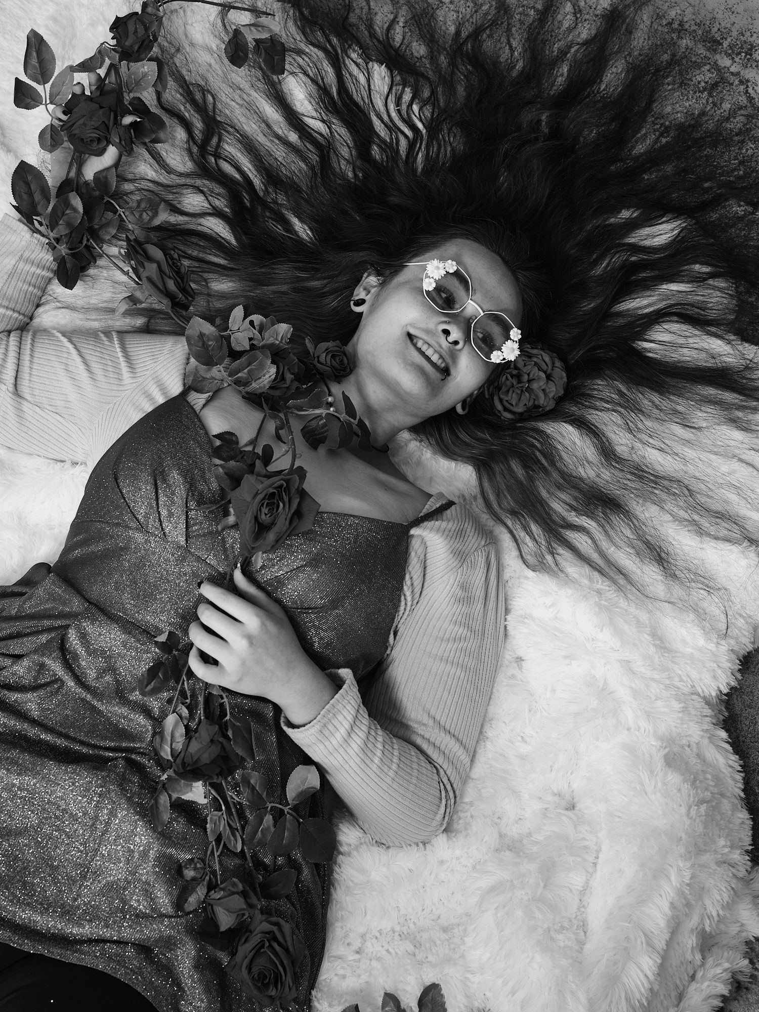 Artistic portrait with flowing hair surrounded by roses in black and white.
