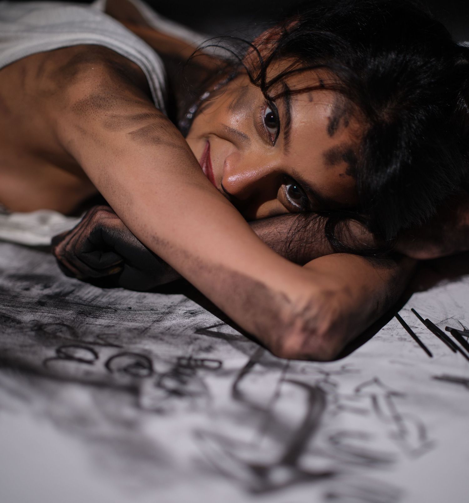 Intimate artistic portrait with charcoal drawings in background.