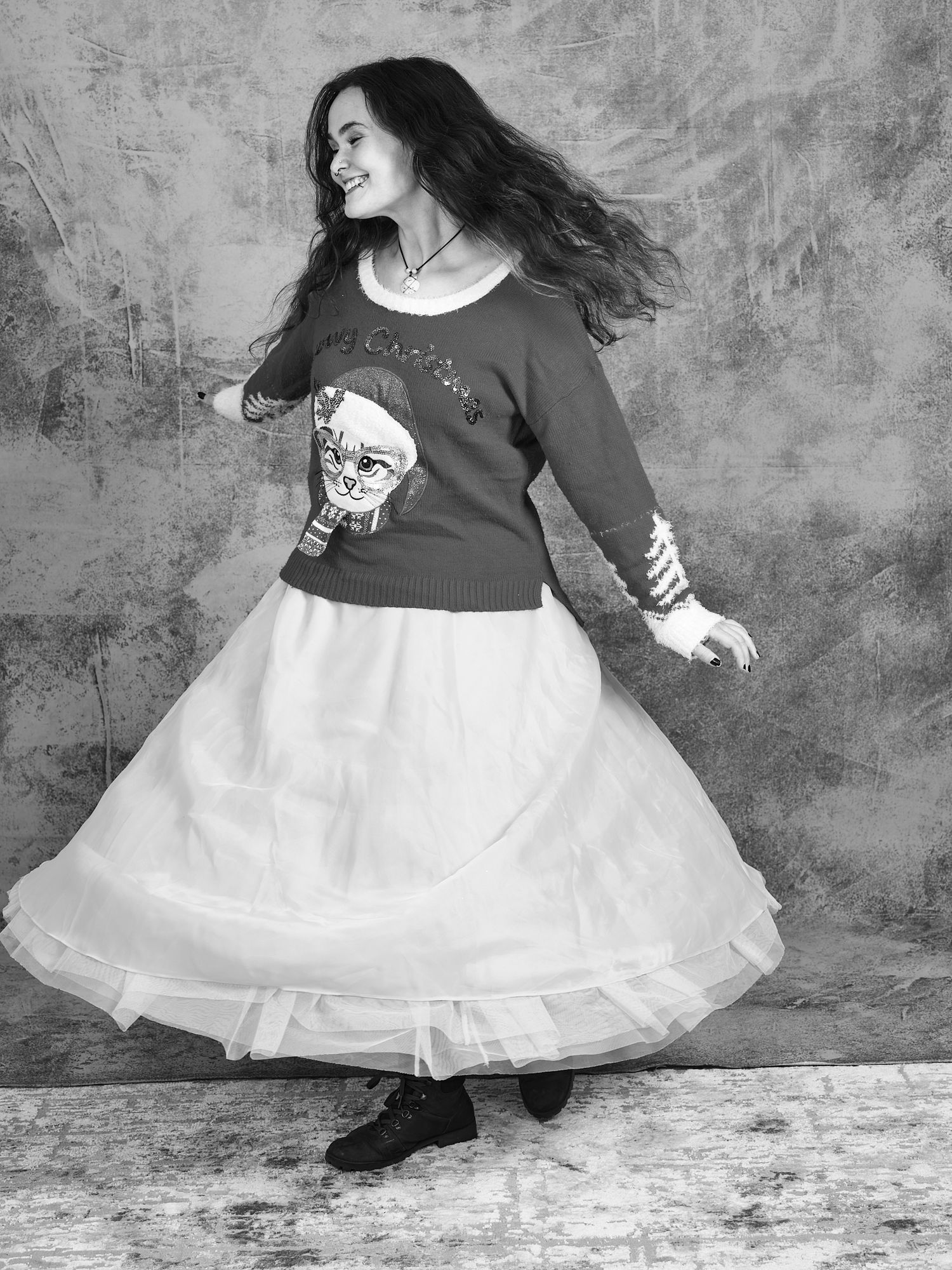 A whimsical black and white portrait of someone twirling in a tulle skirt and graphic sweater.