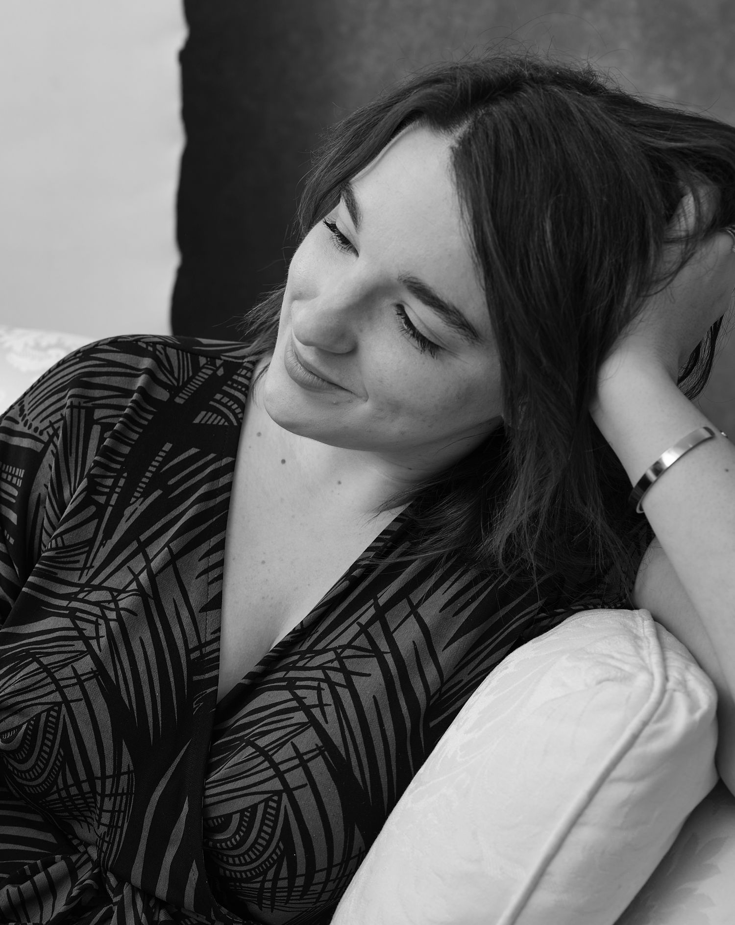 A peaceful monochrome portrait showing a moment of rest against soft pillows.