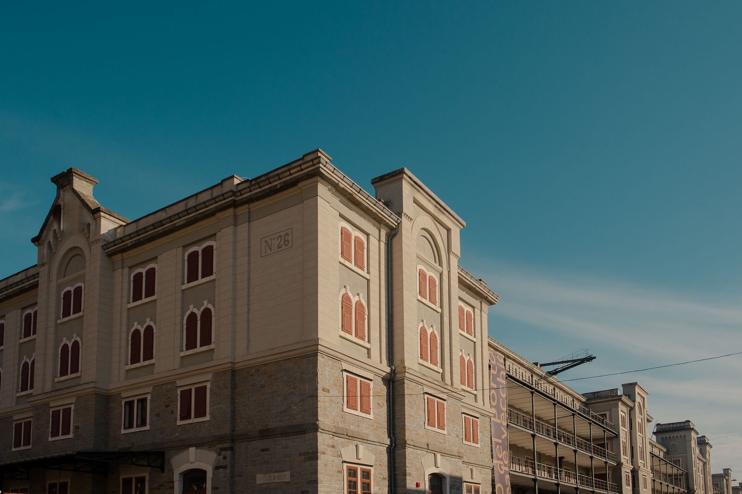 Historic beige building with arched windows and ornate facade against a clear blue sky.