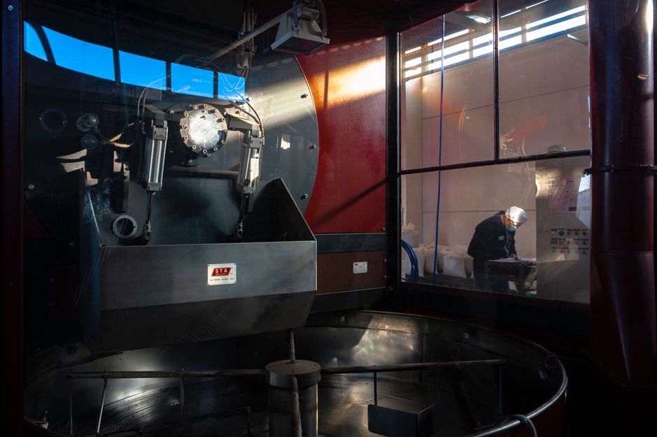Interior view of a train cab simulator with control panels and operator visible through glass windows.