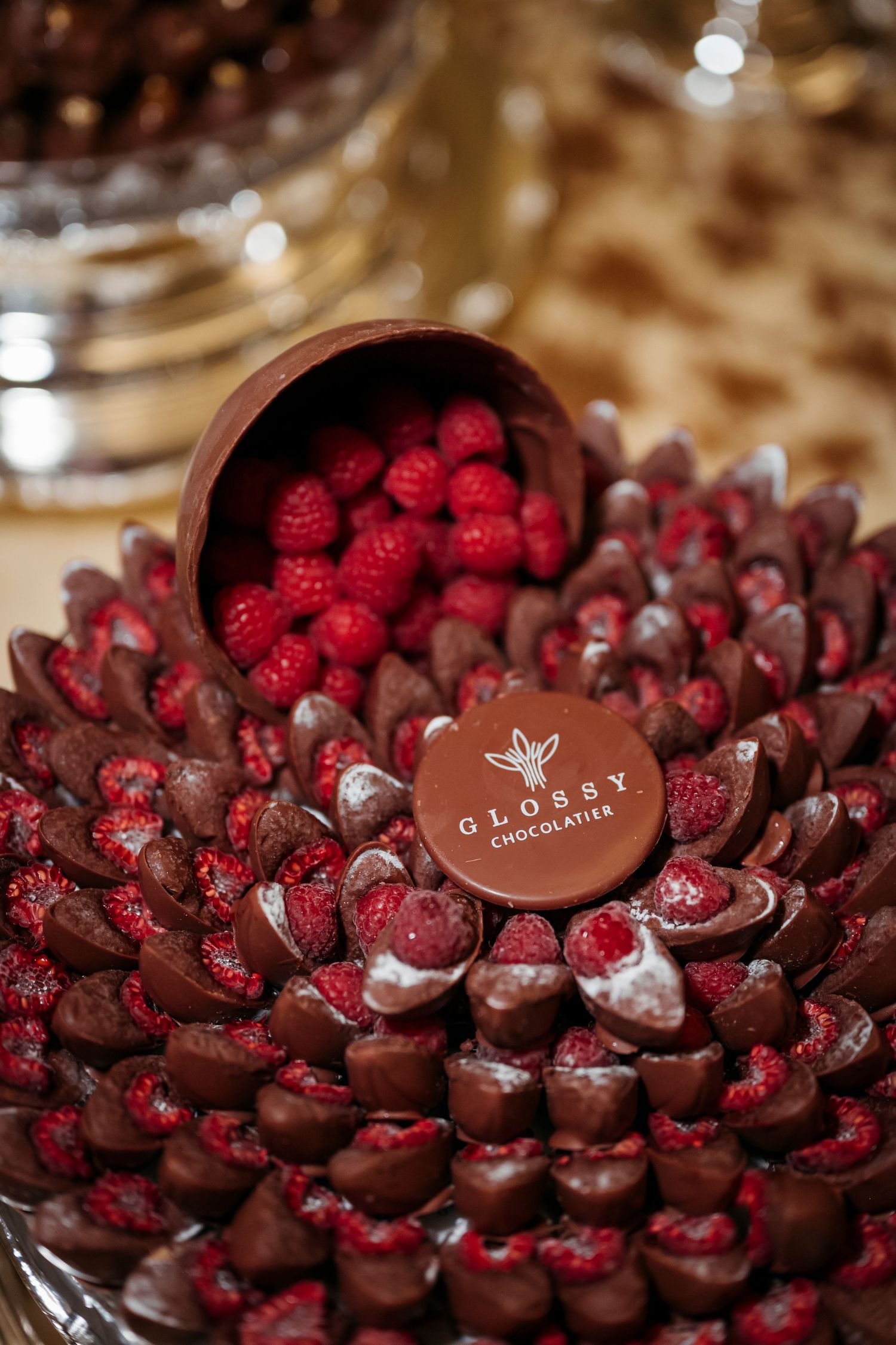 Chocolate covered raspberries arranged in a spiral pattern with glossy chocolate medallions on top.