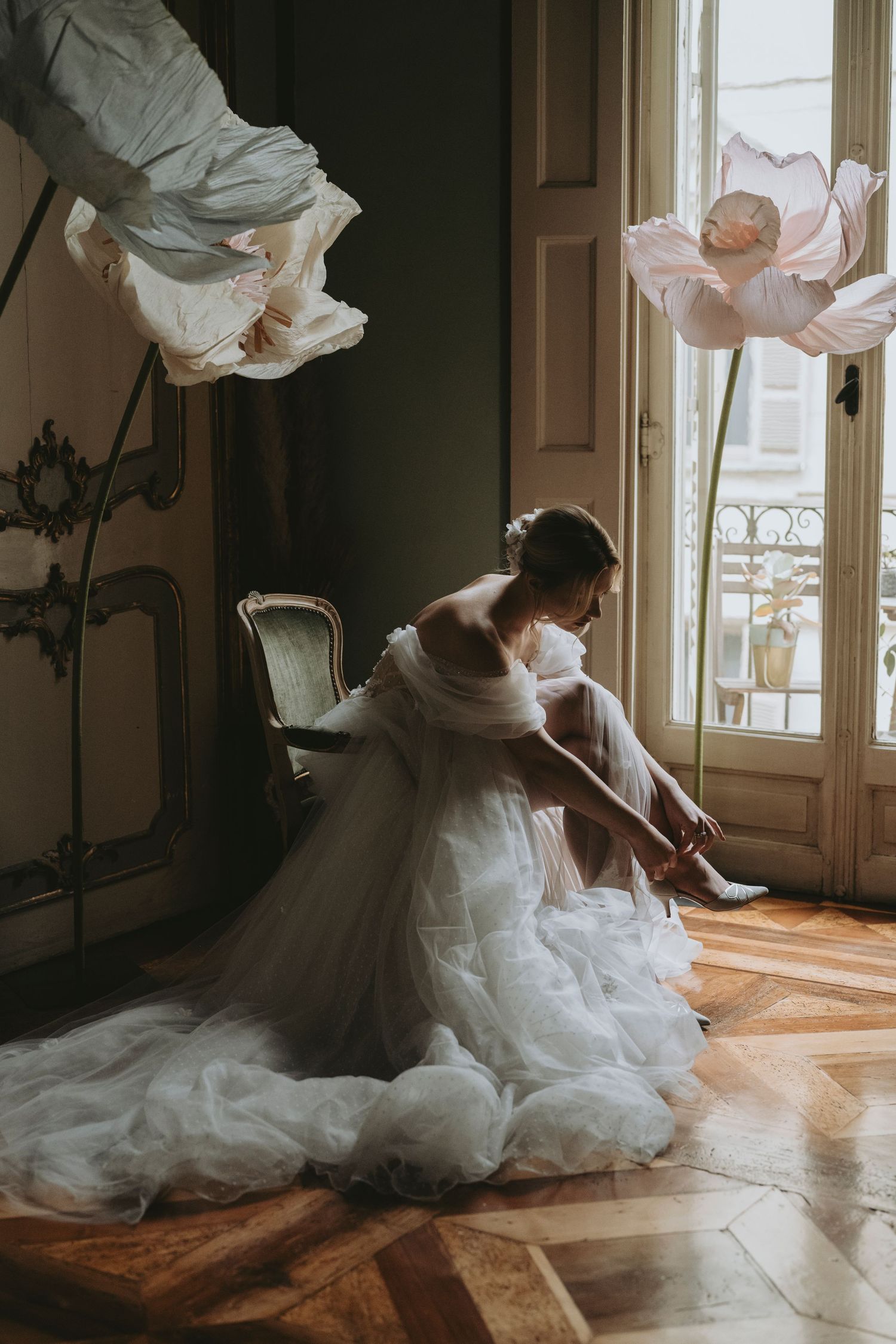 Elegant bride in flowing white dress twirls gracefully across a sunlit hardwood floor in a vintage room.