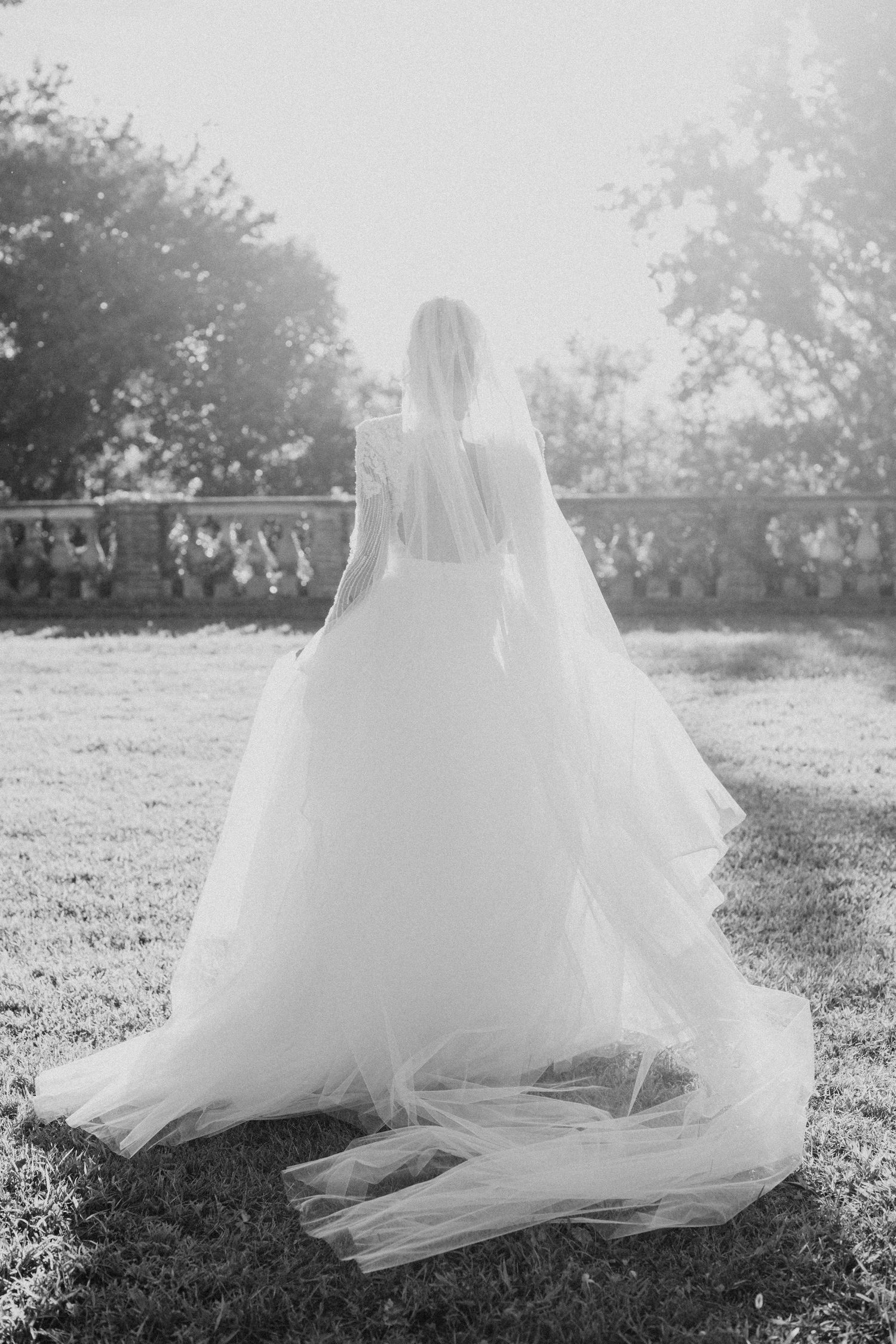 A flowing white wedding veil blows gracefully across green grass in a series of artistic black and white photographs.