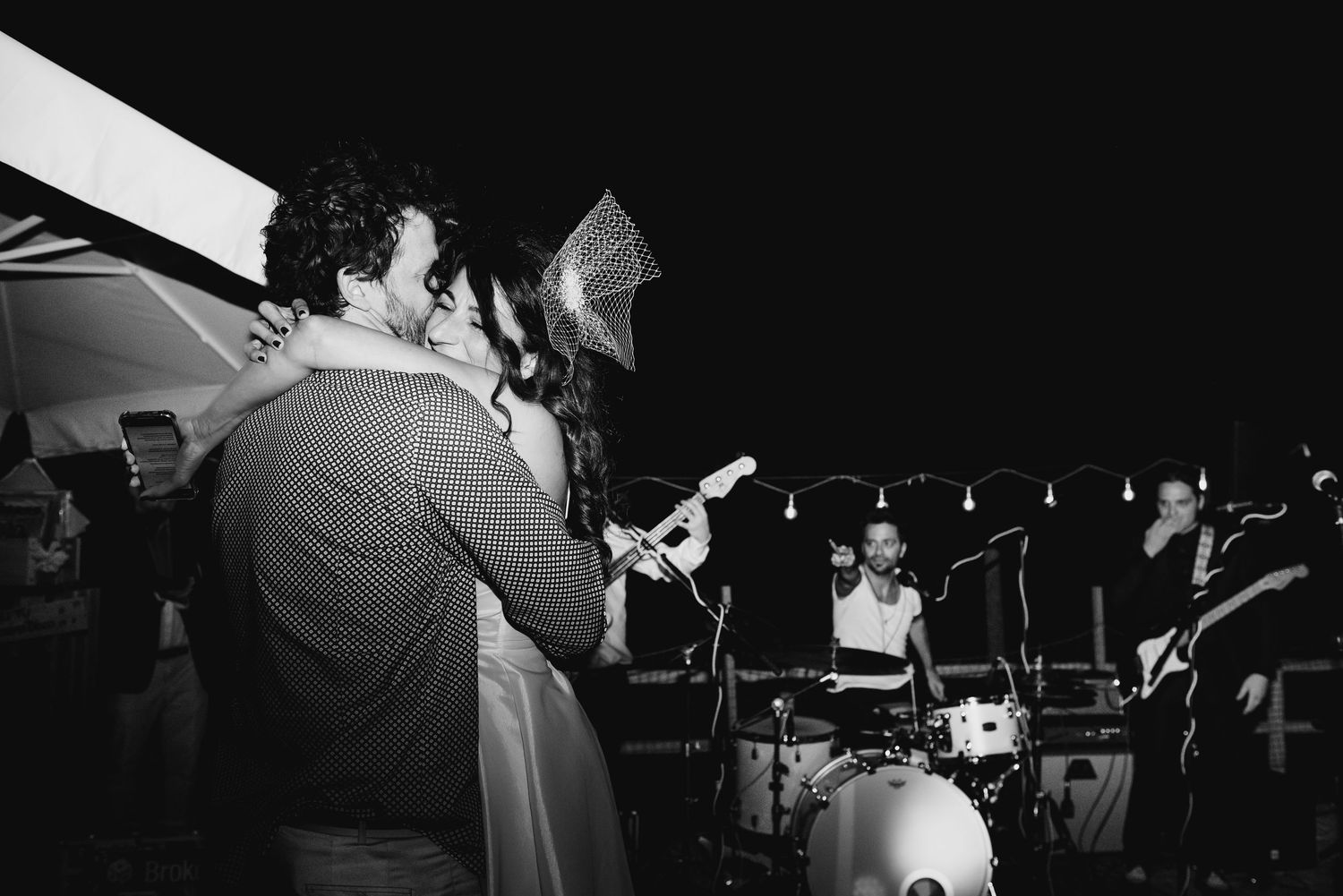 Musicians perform on a dark stage with dramatic lighting during a live concert performance.