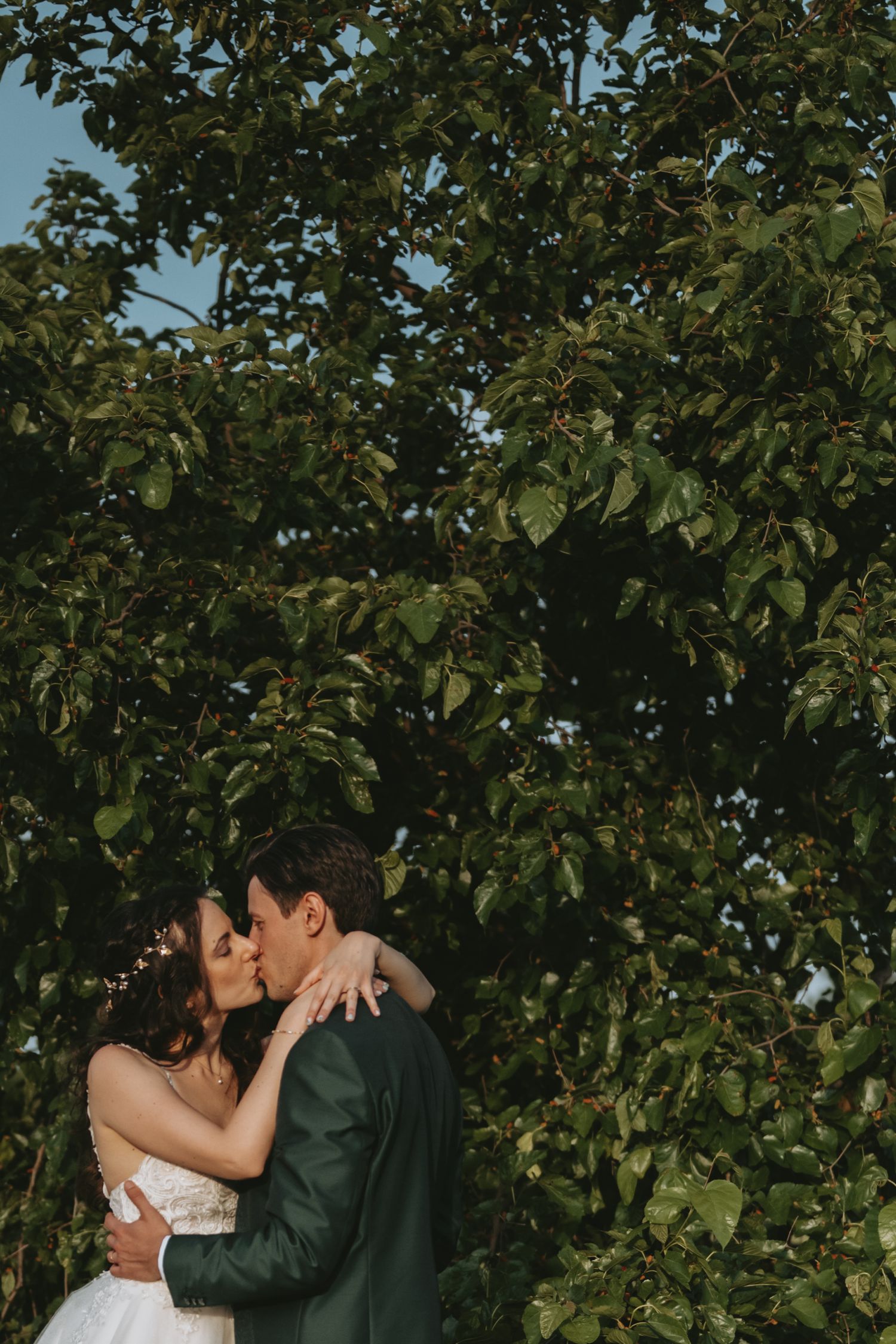 Couple shares intimate moment in lush garden setting with green foliage surrounding them.