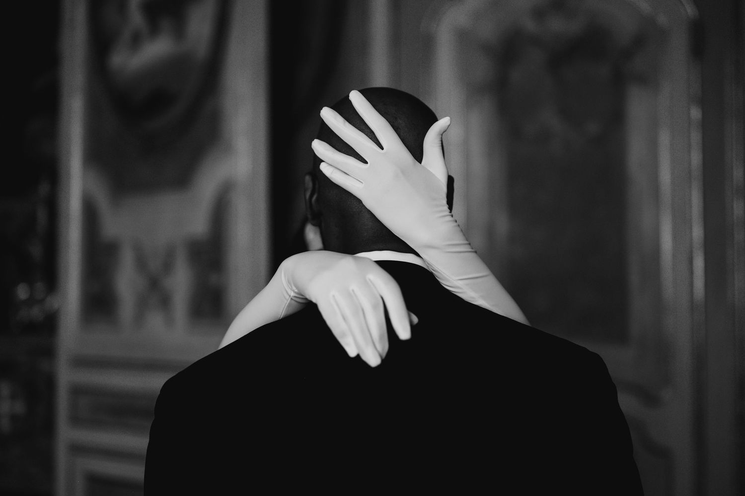 A person wearing a white glove waves their hand against a dark background.