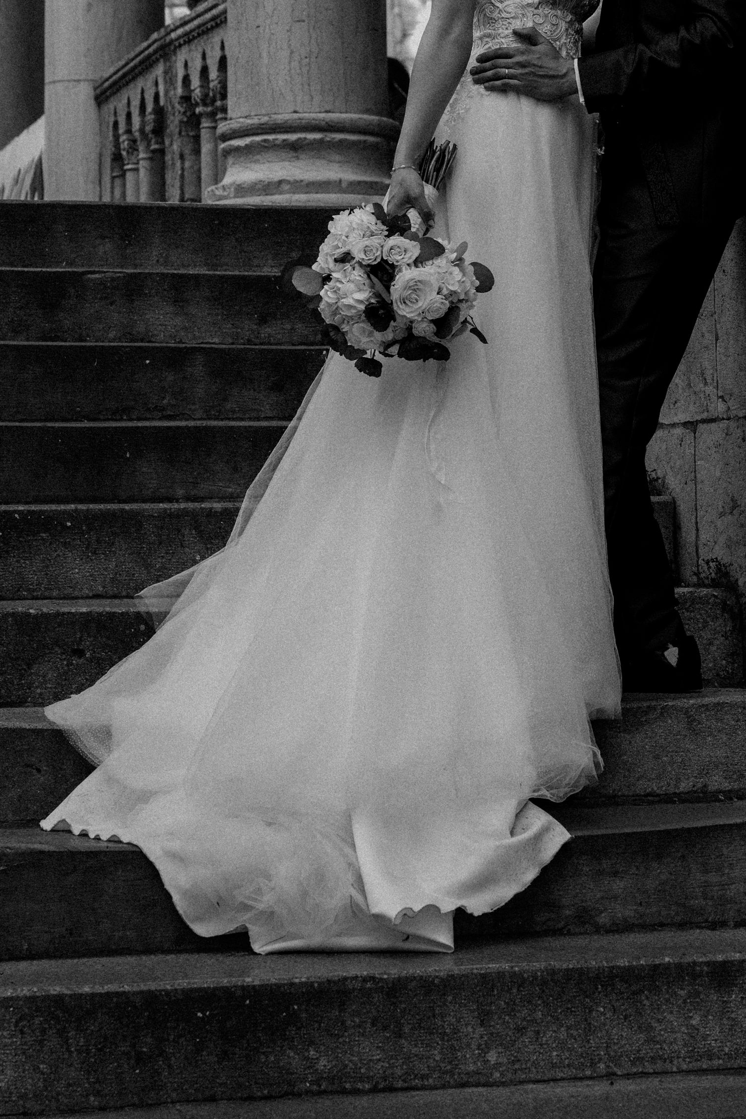 A series of black and white photos showing the bottom portion of a wedding dress as it cascades down stone steps.