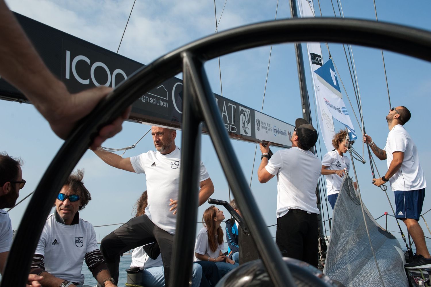 Sailors work together on a racing sailboat deck, adjusting rigging and sails during a competitive sailing event.