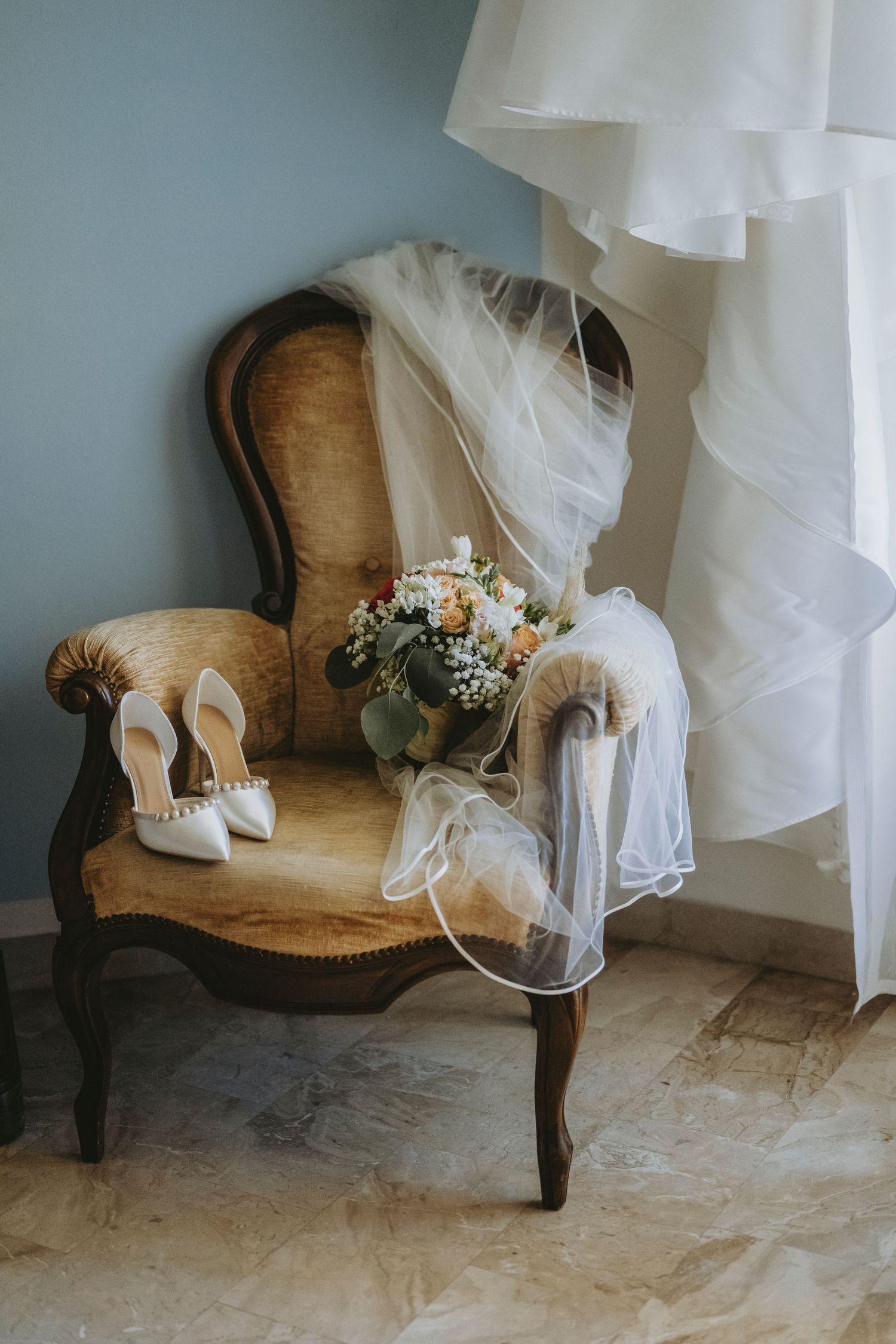 A vintage brown chaise lounge decorated with white wedding accessories including veils and floral arrangements.