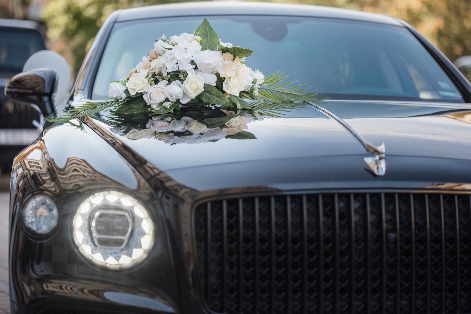 Luxury black wedding cars adorned with white floral decorations parked in a row.