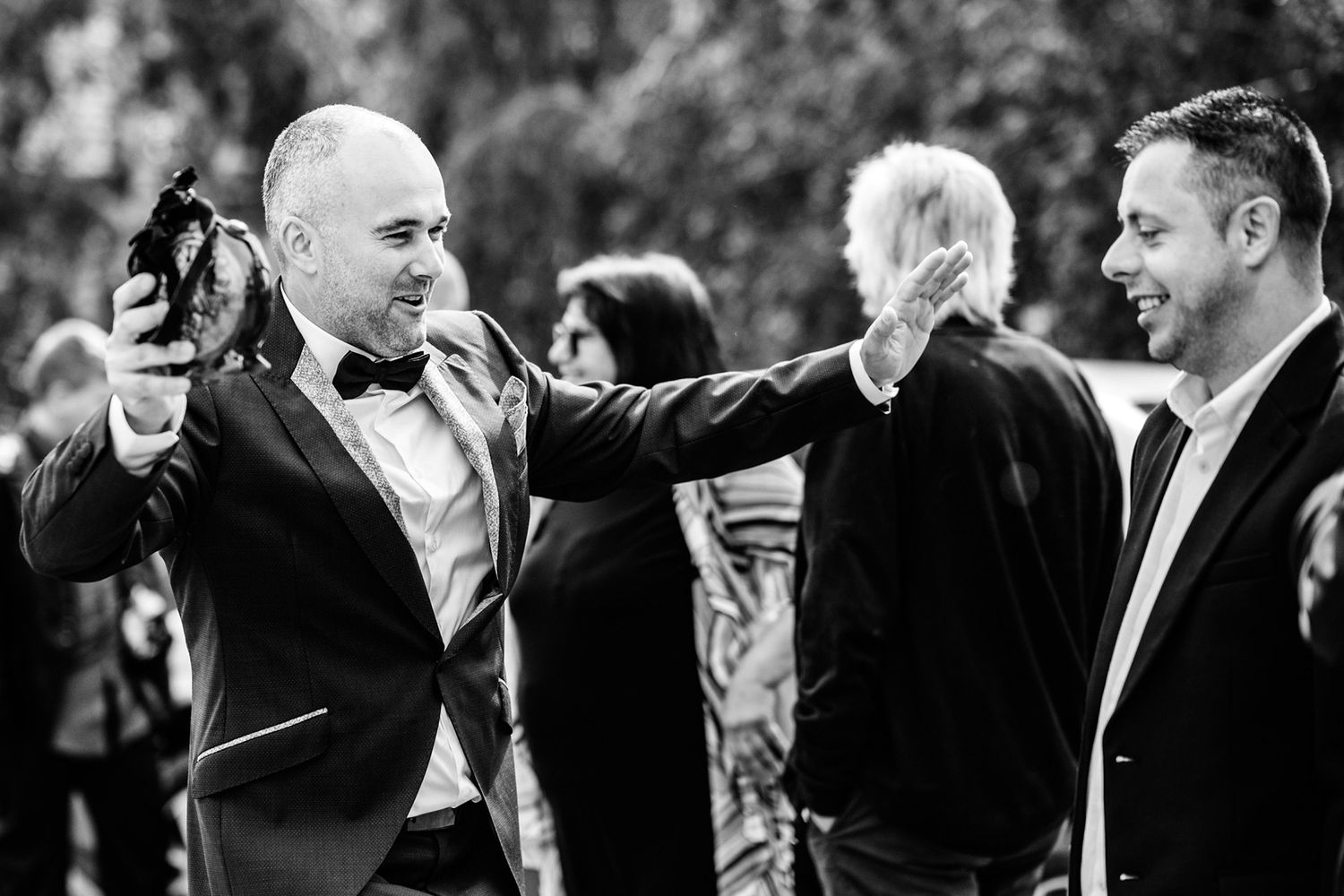 Black and white photo of guests in formal attire sharing a candid moment at an event.