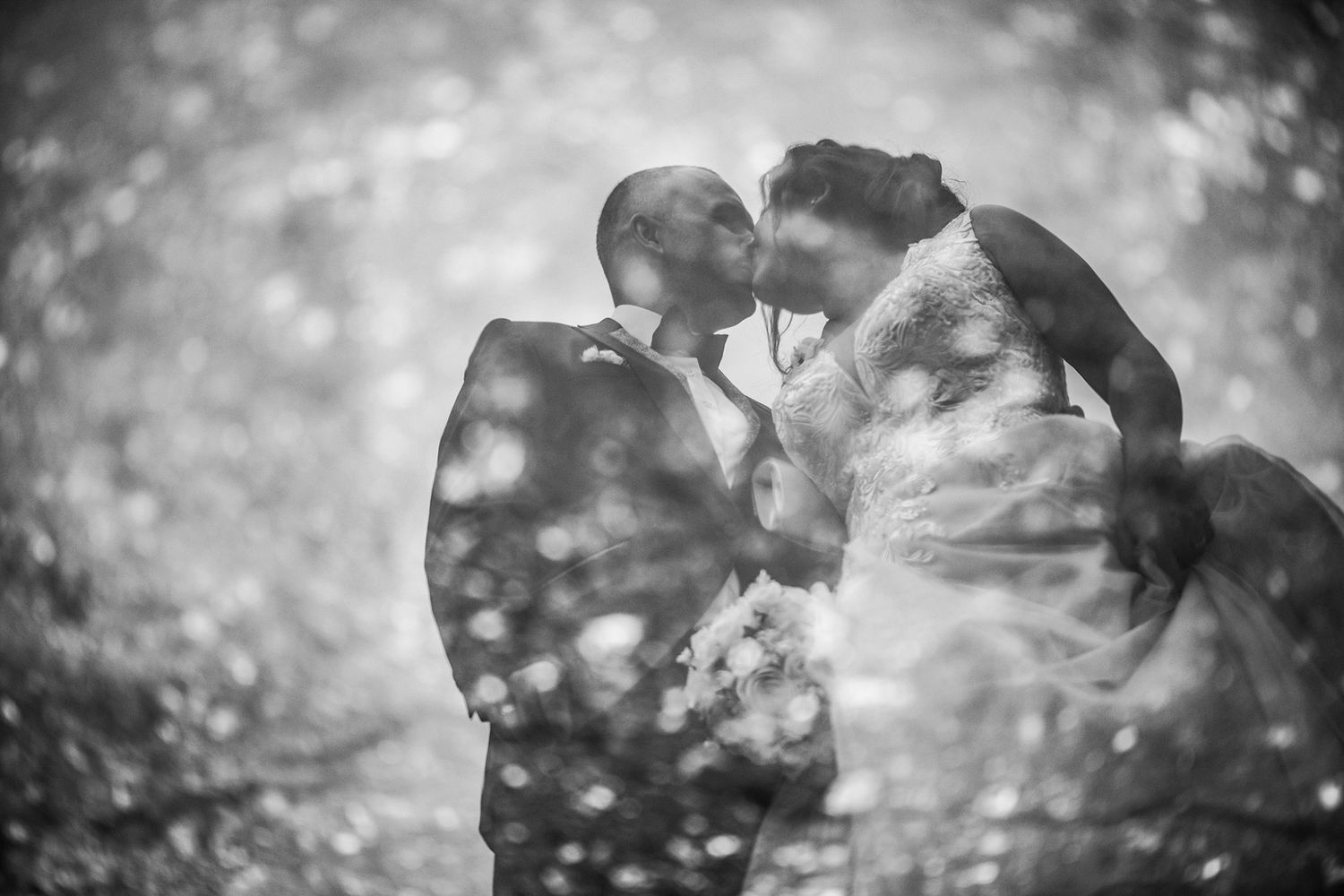 Black and white artistic silhouette of wedding couple with bokeh effect.
